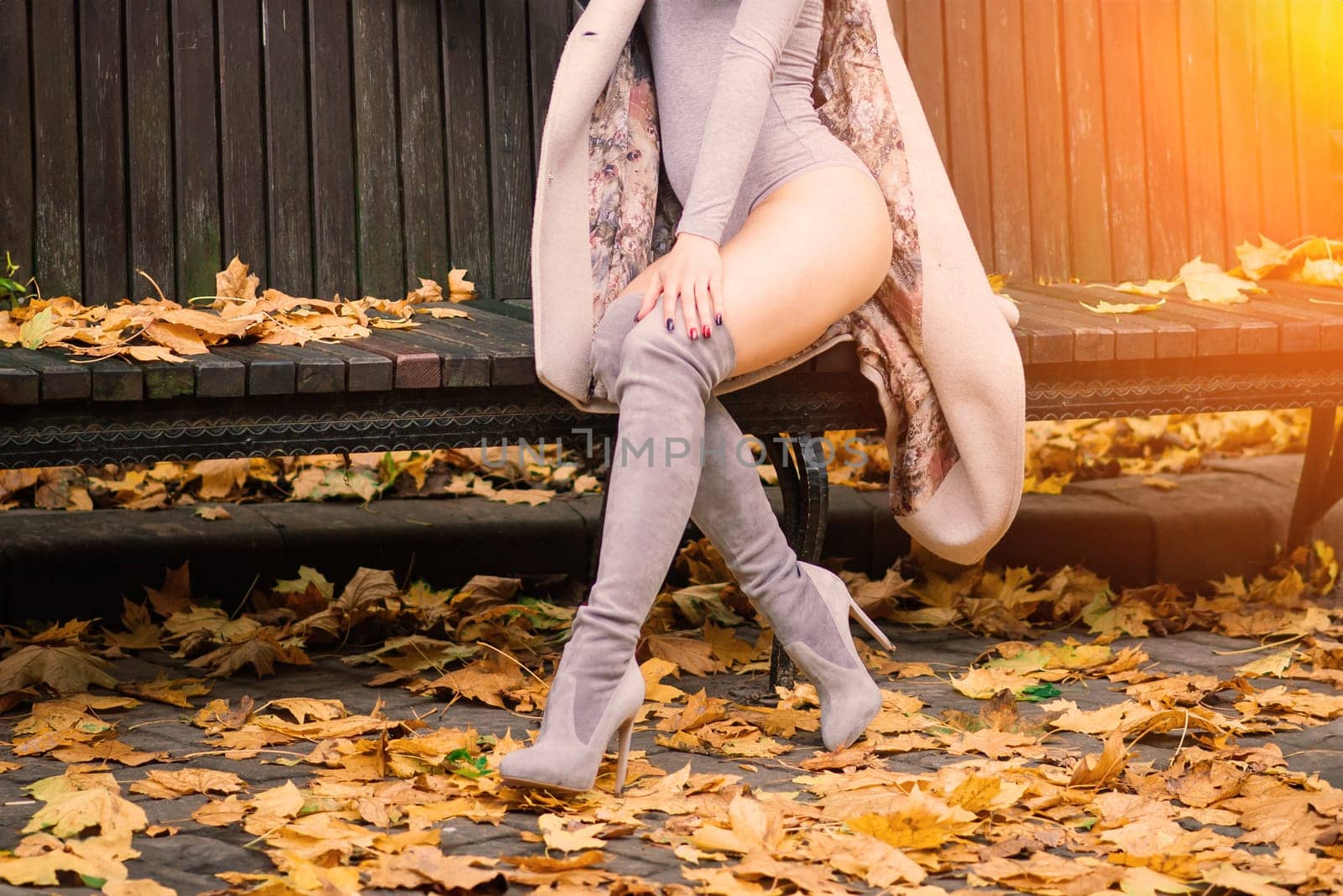 Young beautiful dark-haired woman with a slender figure posing in lingerie and a classic coat in an autumn park