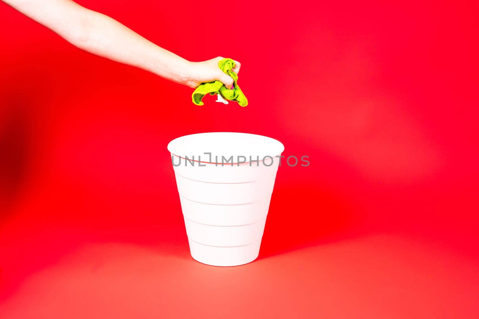 Throw napkin in a trash bin, house cleaning rag in hand in front of trash can, cleaning concept