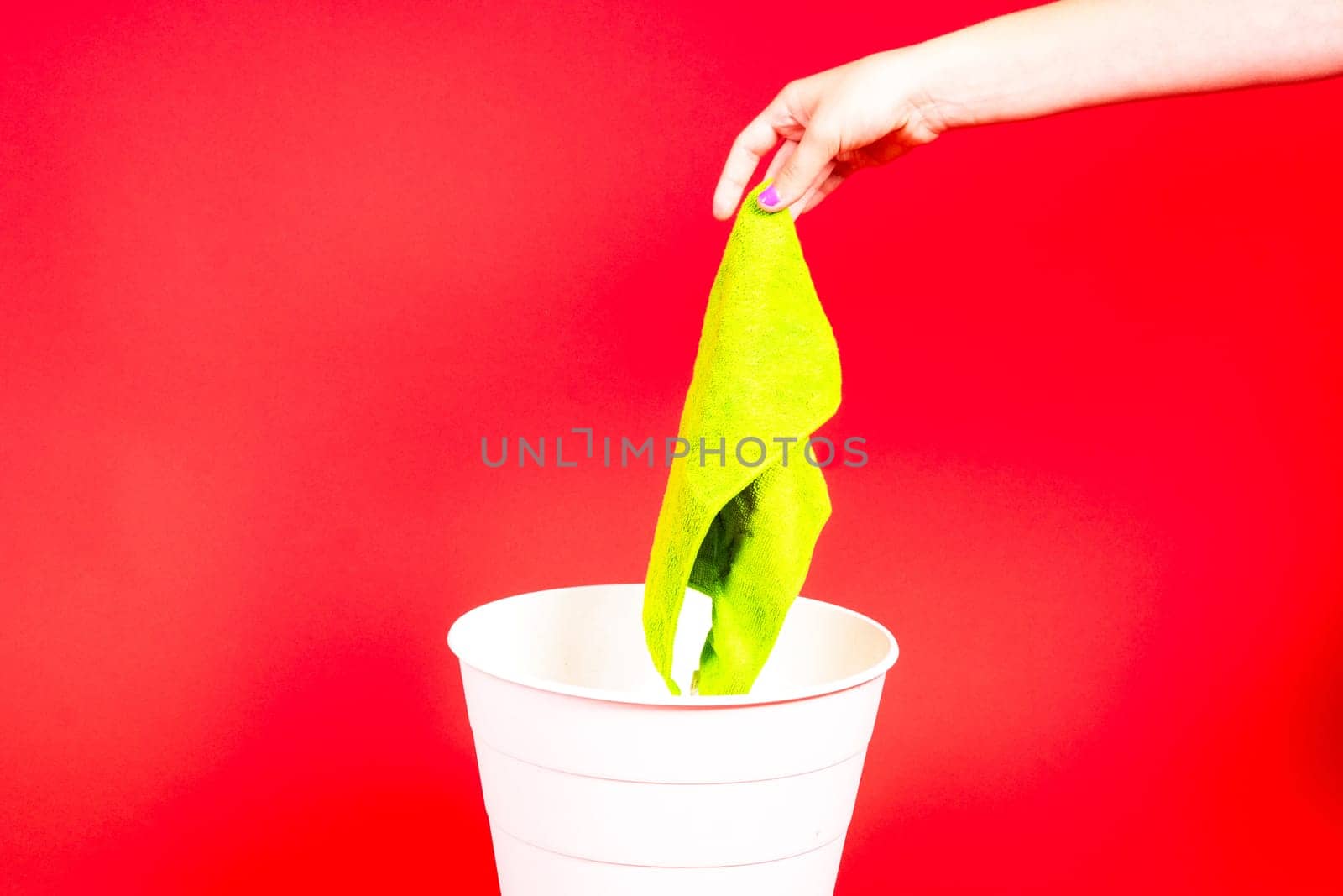Throw napkin in a trash bin, house cleaning rag in hand in front of trash can, cleaning concept