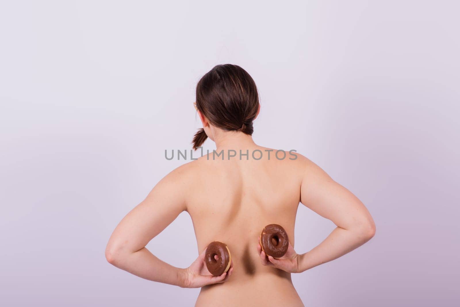 Close up shot of nude topless woman holding chocolate covered donuts