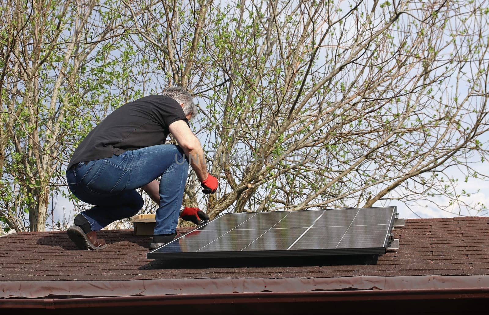 A man installs a solar system to generate electricity on the roof of a garden shed