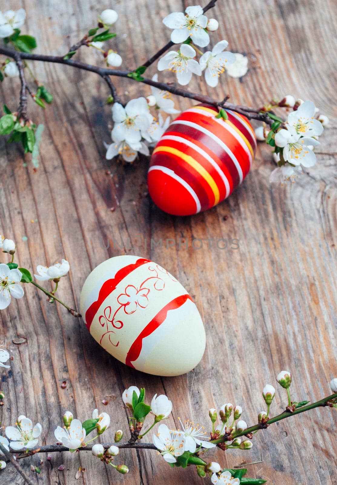 Top view of colorful painted easter eggs and cherry blossom branch decor on vintage wooden table. Traditional seasonal holiday still life from above. Easter celebrate and spring concept.