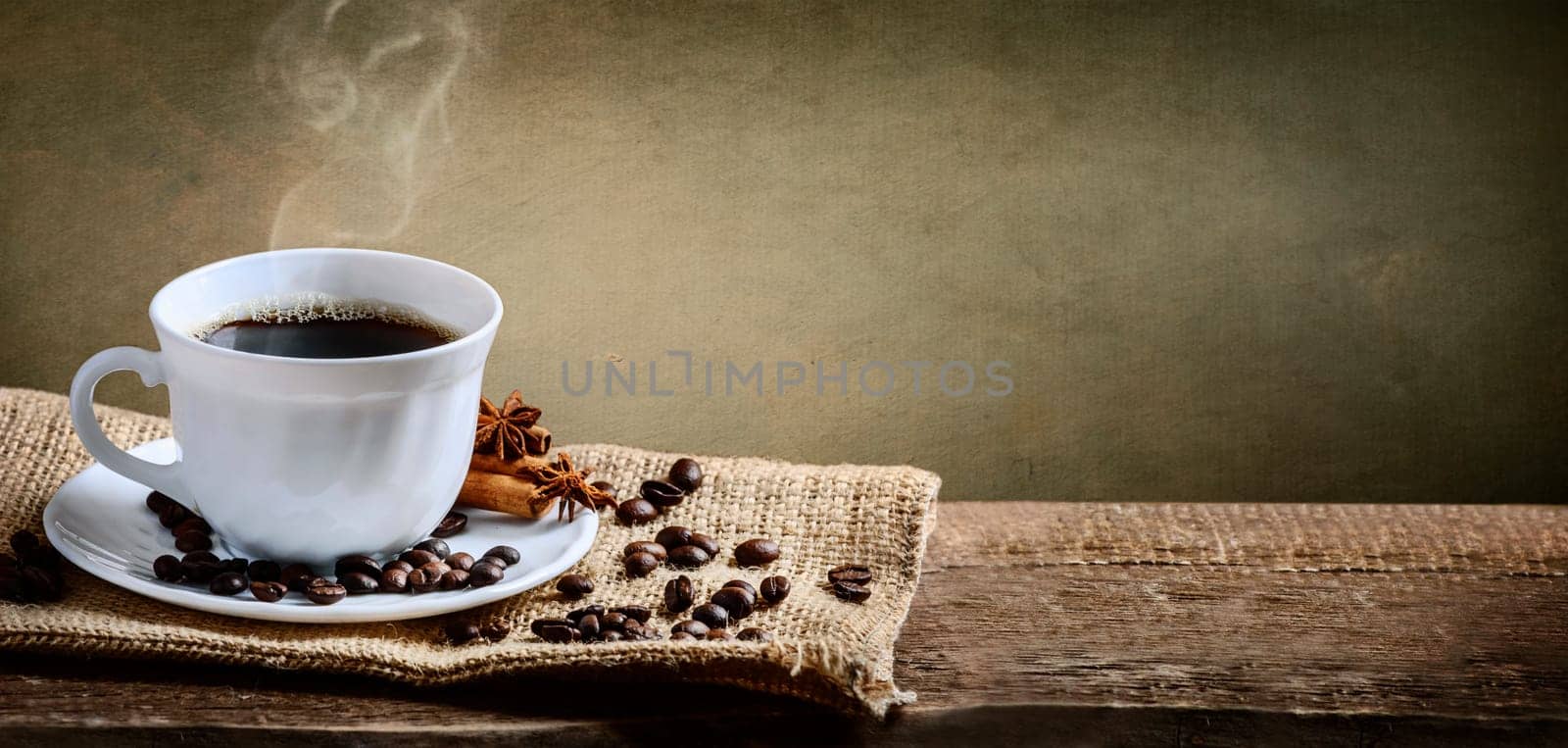 Coffee cup, cinnamon and anise on old burlap and rustic wooden table. Hot beverage banner. Vintage coffee shop menu design background.