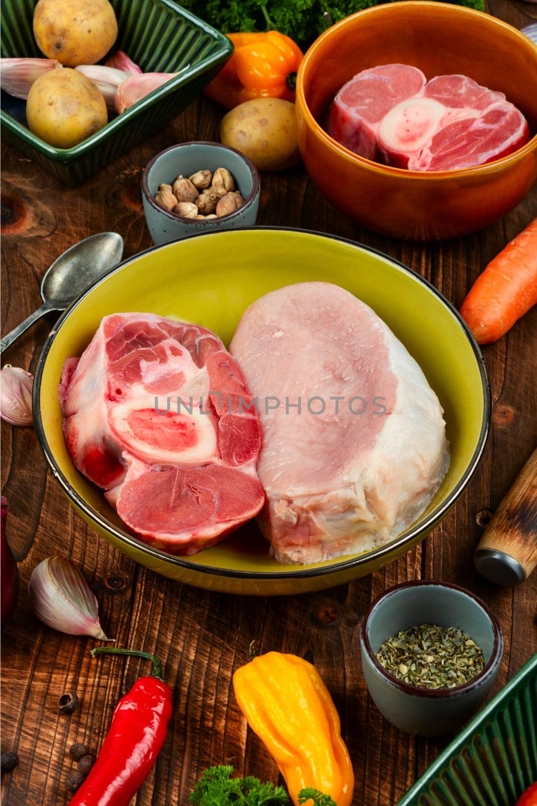 Raw piece meat and vegetables on the kitchen table. Set of ingredients for soup or borscht on old rustic wooden table.