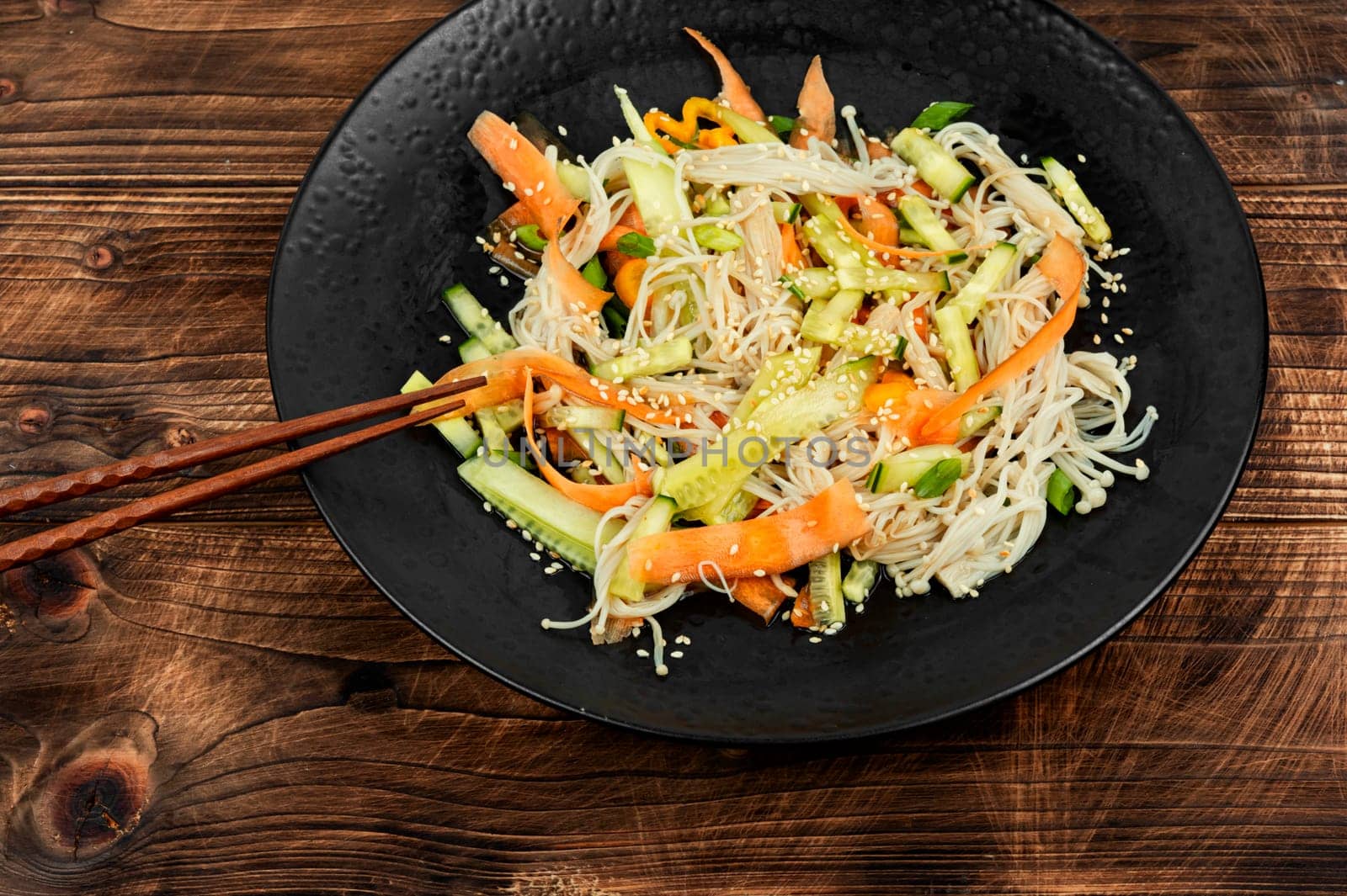 Plate with salad of enoki mushrooms and vegetables. National Chinese food. Flammulina velutipes salad. Close up.