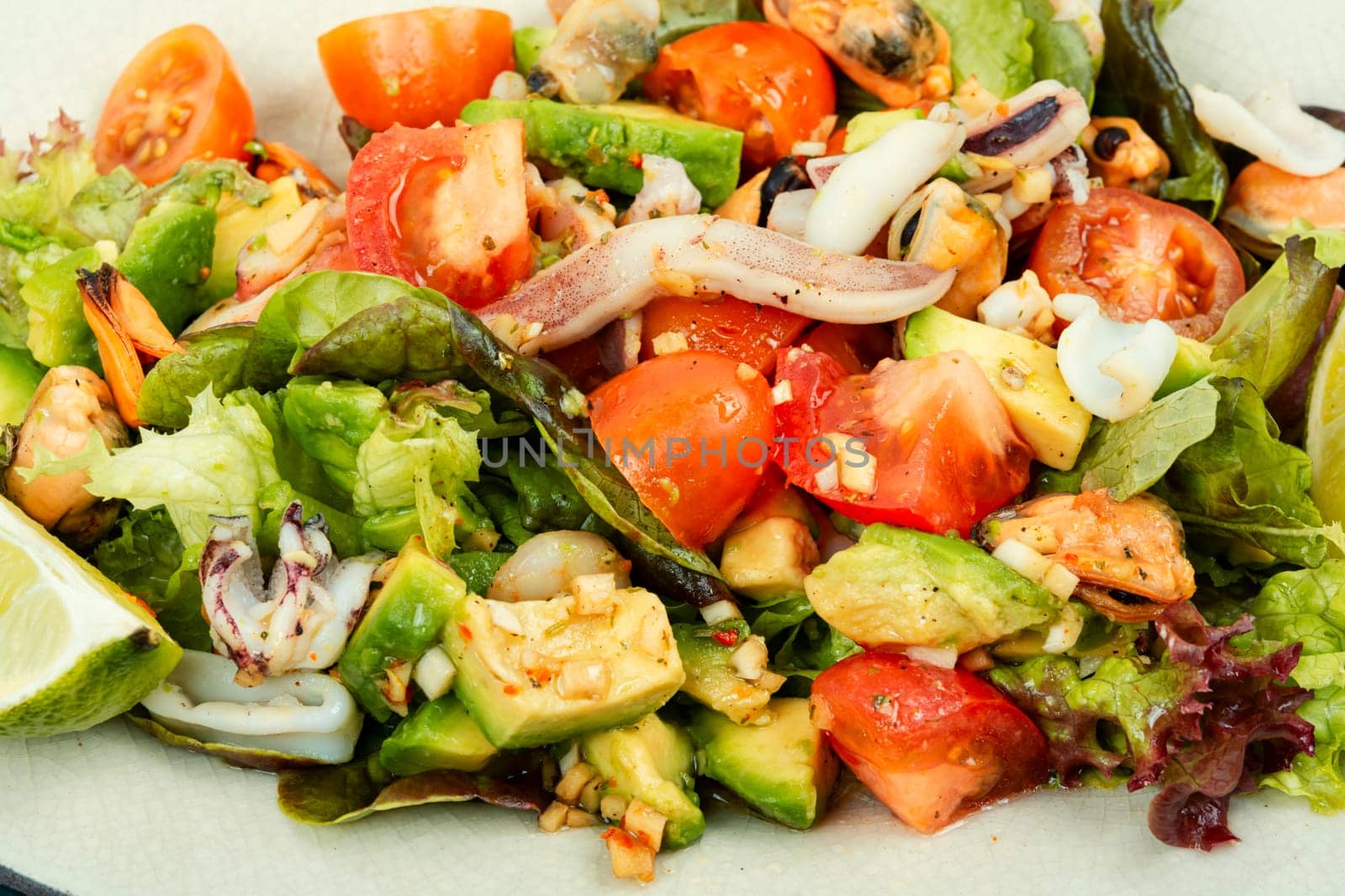 Delicious salad with fresh vegetables and seafood on a plate. Close up.