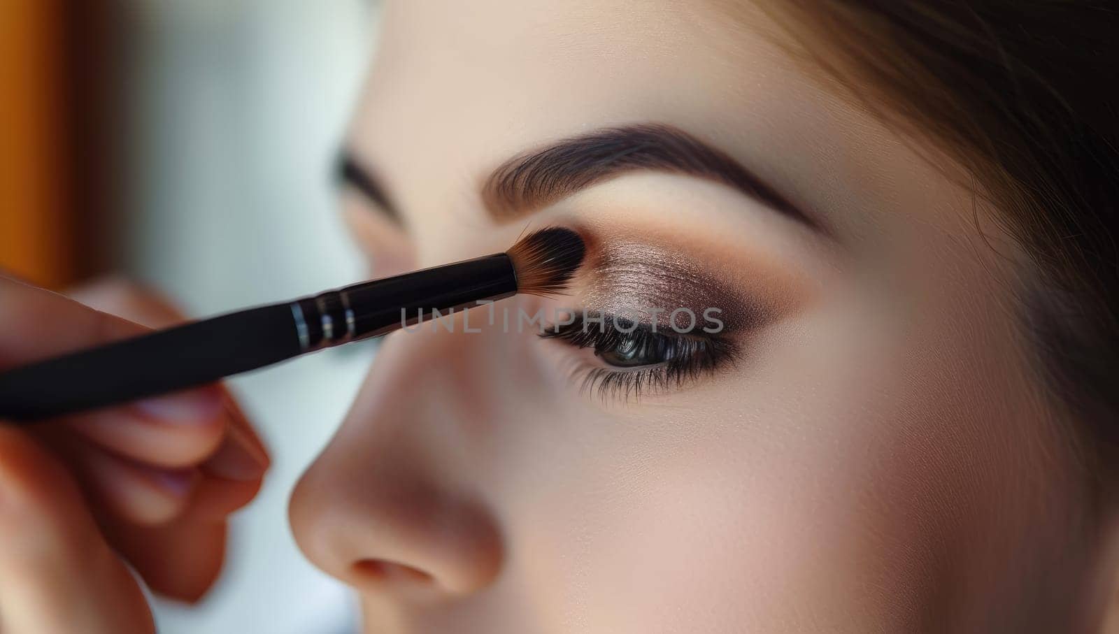 Make-up artist applying mascara on eyelashes of young beautiful woman
