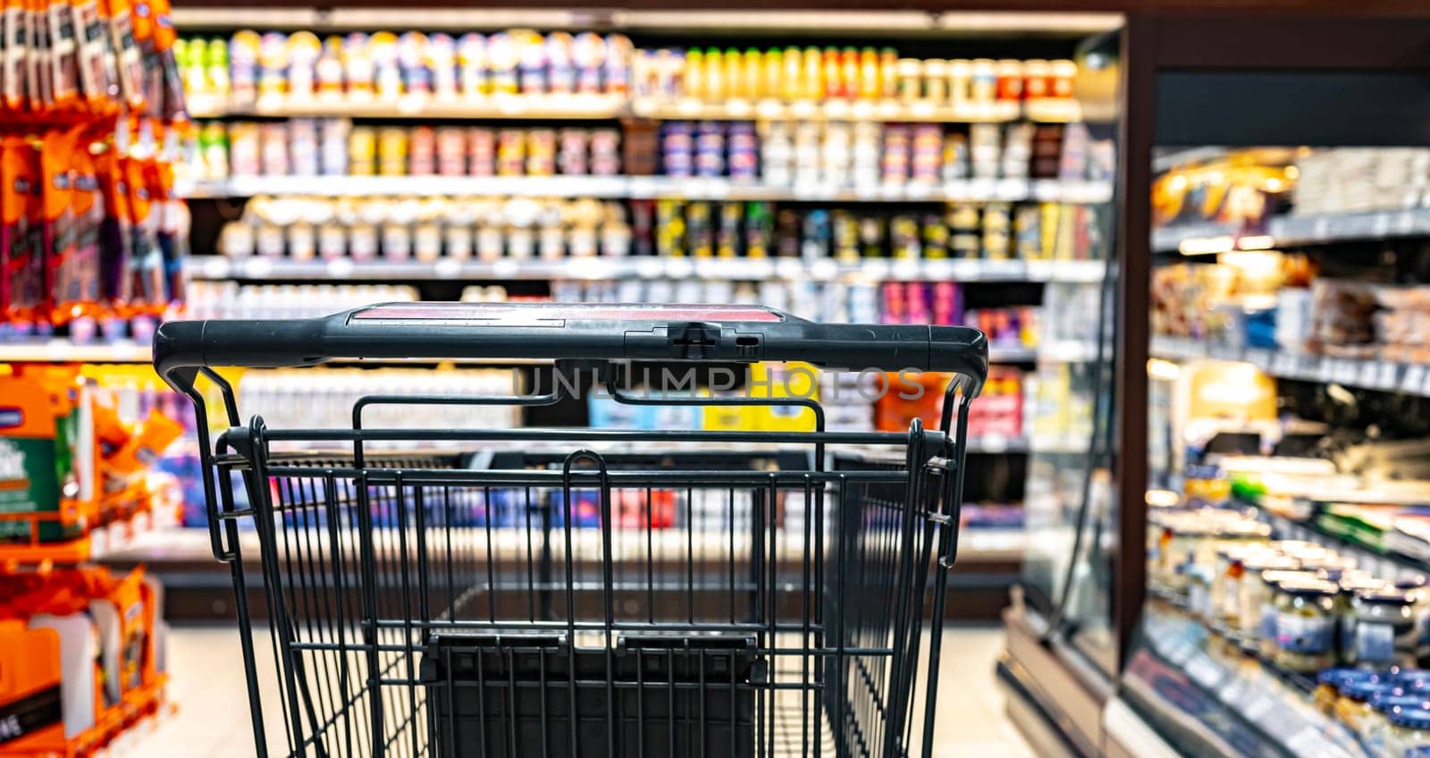 A shopping cart by a store shelf in a supermarket