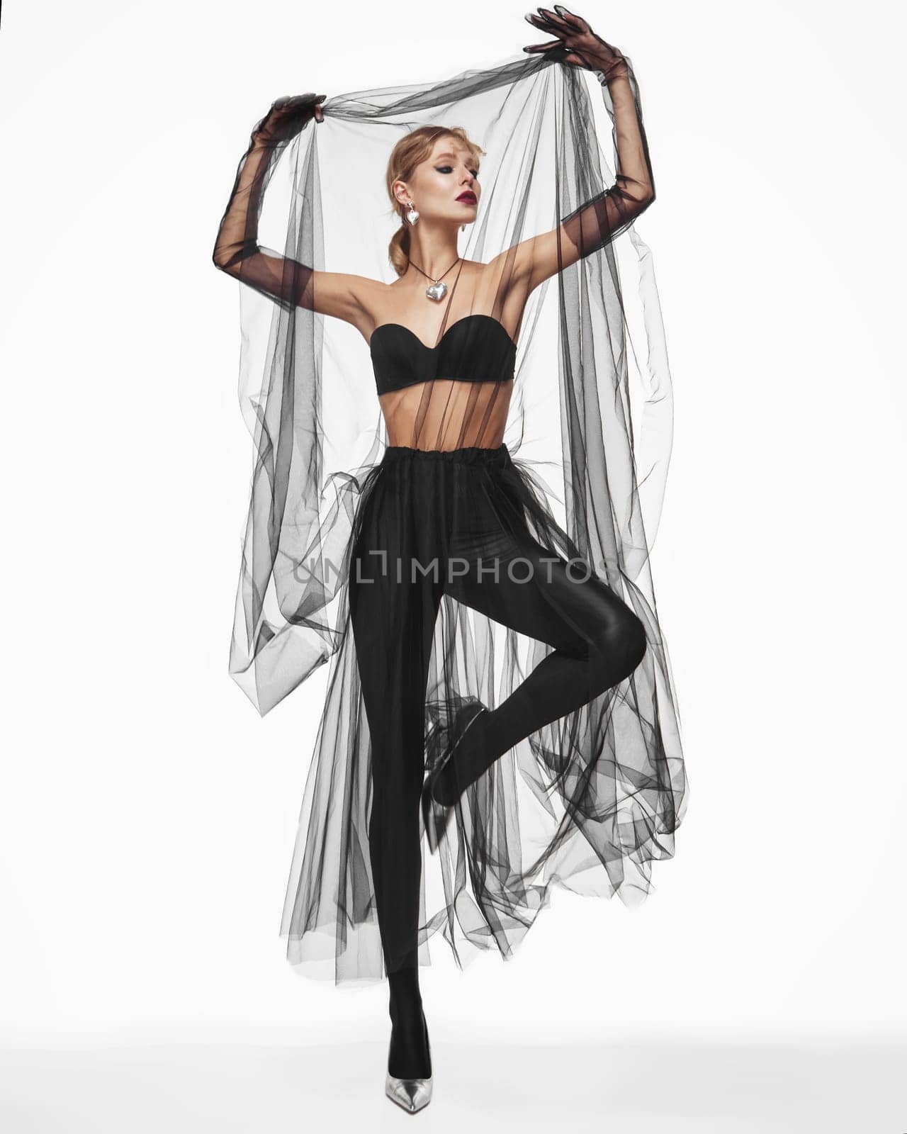 Beautiful woman in a transparent black skirt, bodice and neck decoration posing on a white background.