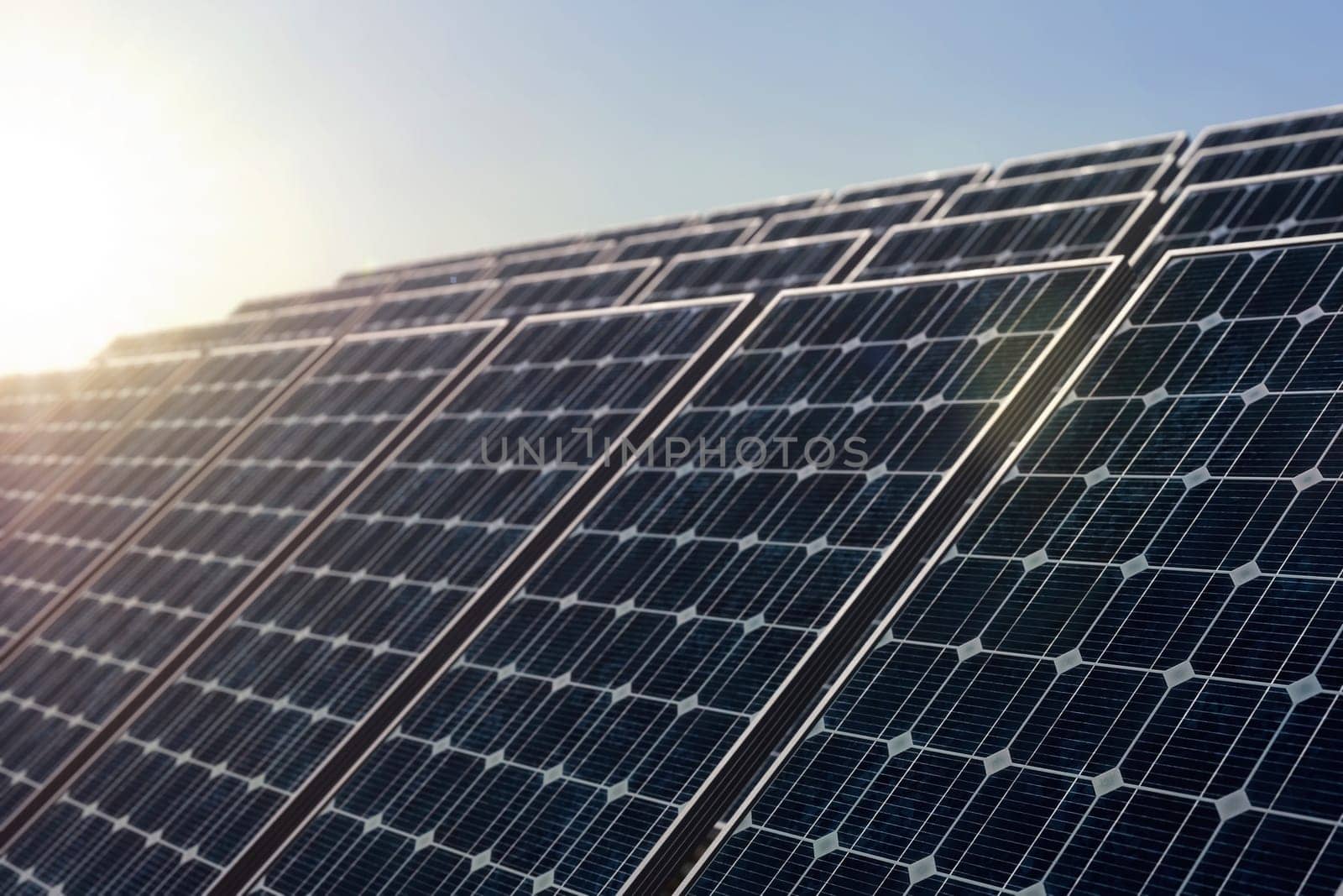 Solar power plant against the rising sun, selective focus on the first solar panel. Alternative energy concept, 3d rendering