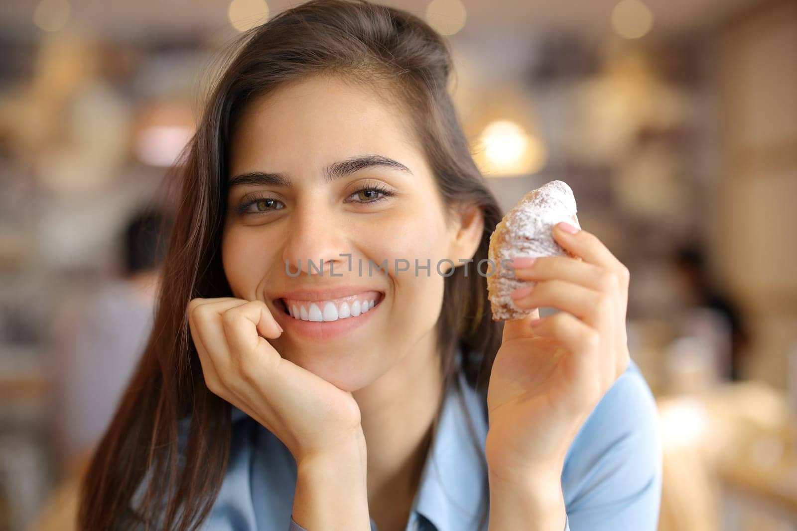 Happy woman smiling holding snack and looking at camera in a bar interior