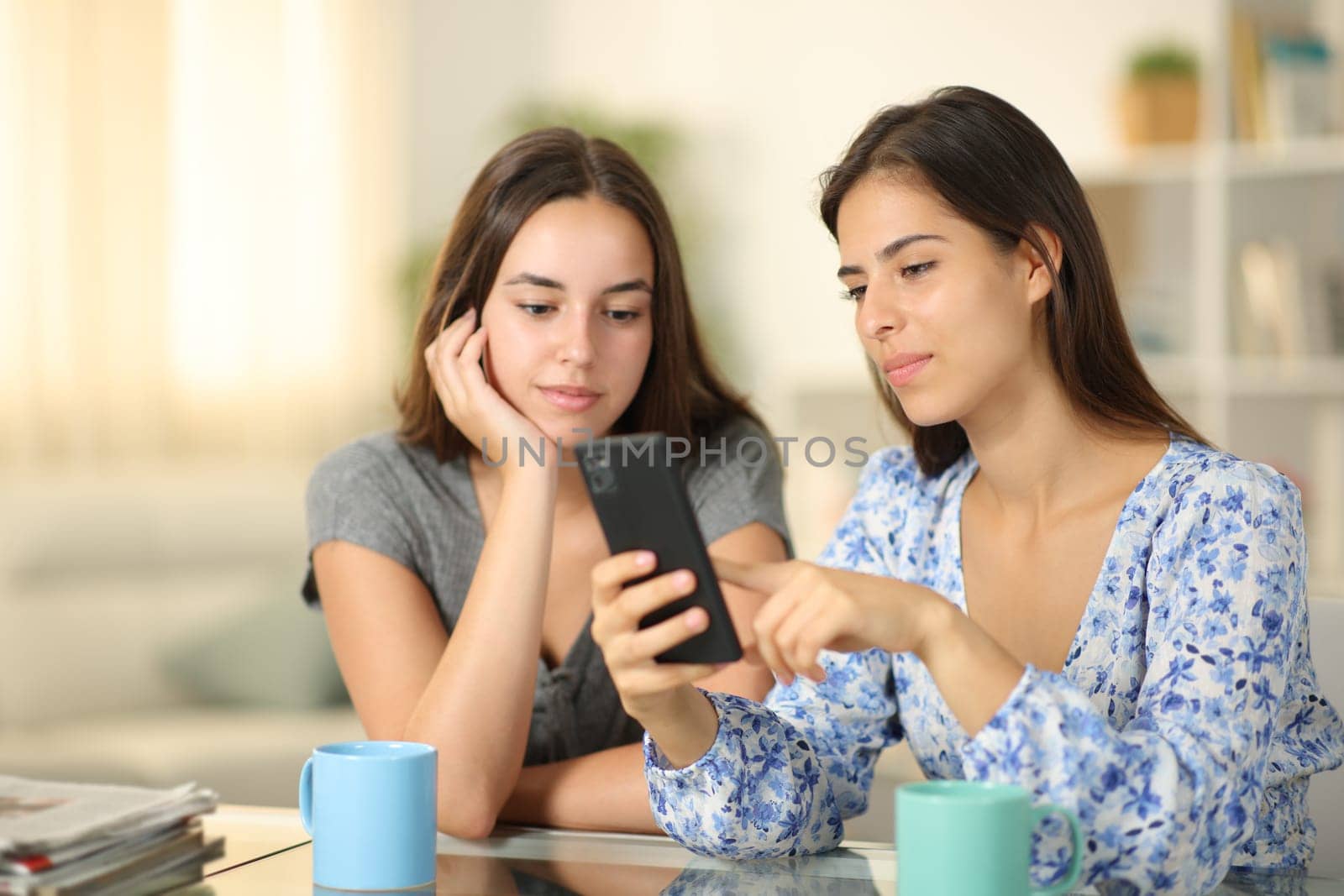 Serious friends checking phone content at home