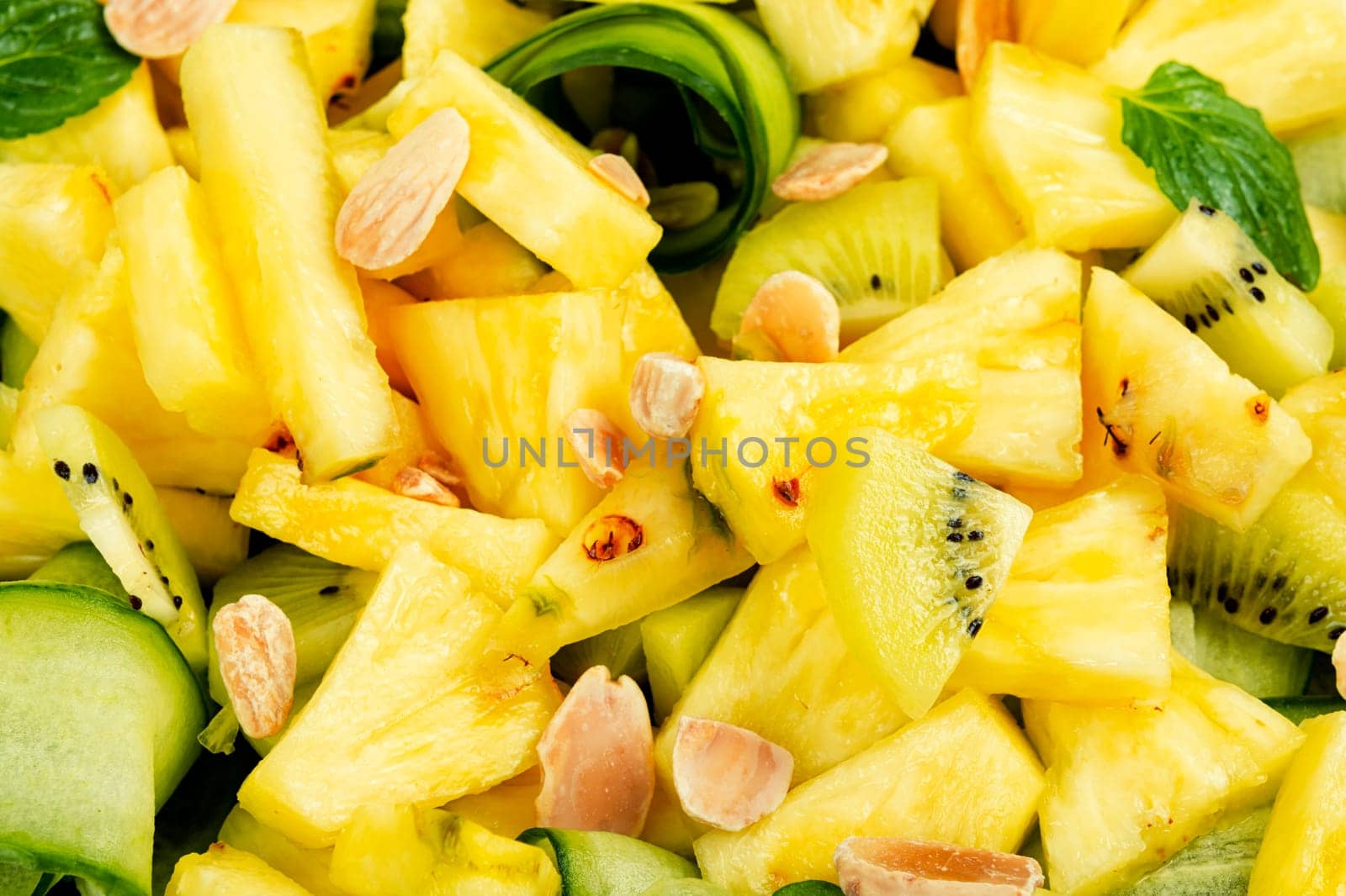 Vegan fresh pineapple and cucumber salad. Pineapple salad served on a black plate and chopstick.