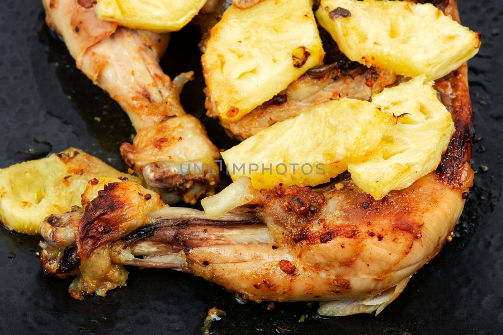Roasted quarters chicken legs with pineapple slices. Baked chicken meat. Close up.