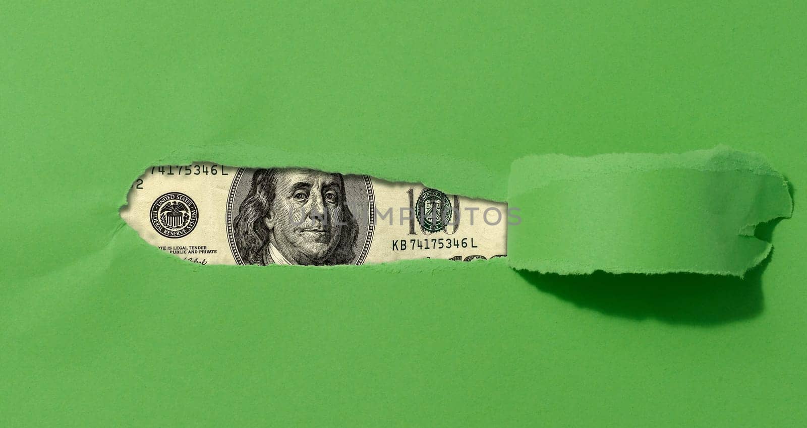 A green sheet of paper with a torn middle and a curled edge, a hundred dollar bill in the hole.
