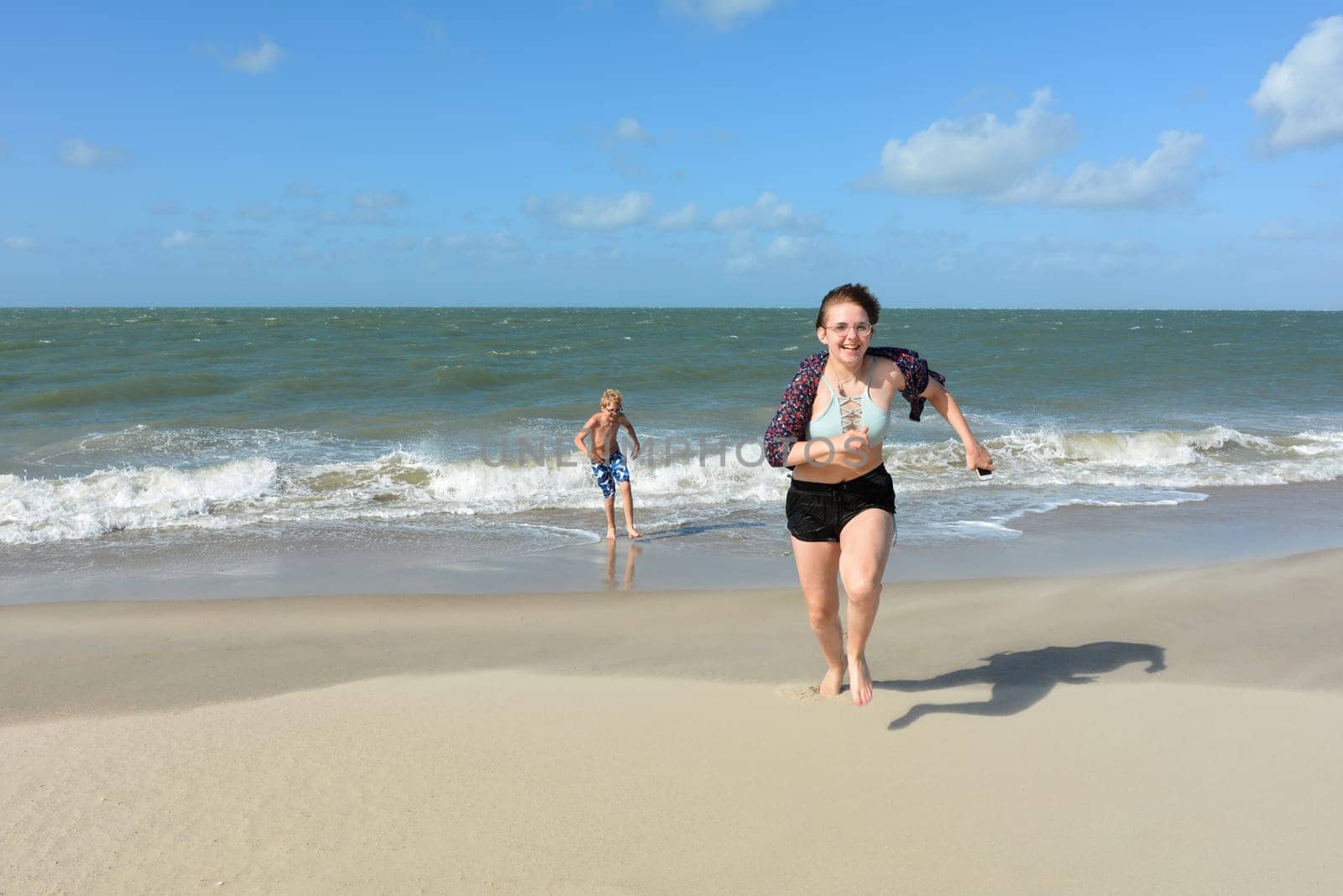 Two children have fun in the waves on the sea beach, Children run out of the water