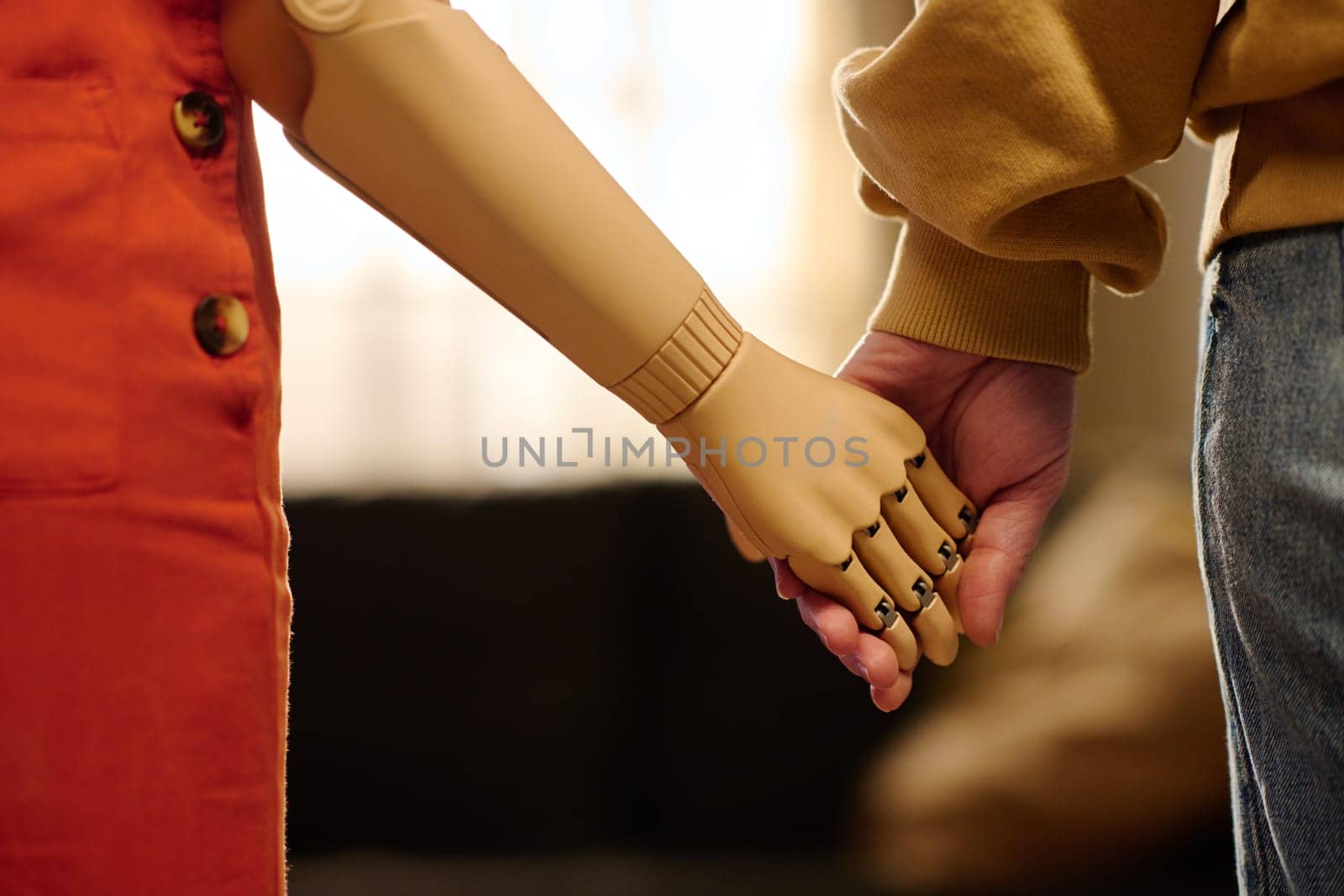 Adolescent girl with myoelectric arm holding her mother by hand while both standing in front of camera