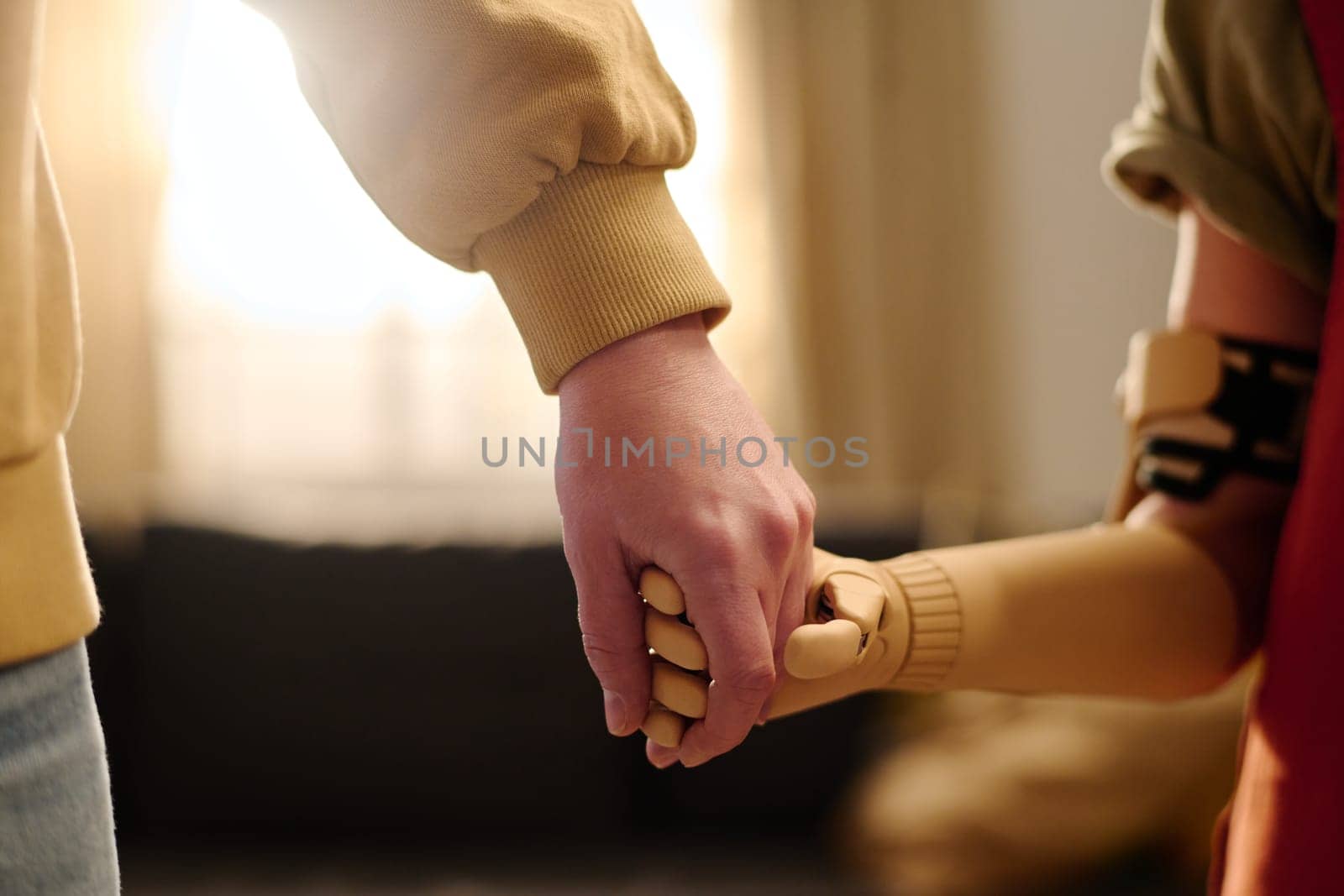 Little girl with partial arm holding her mother by hand while both standing or walking in front of camera in home environment