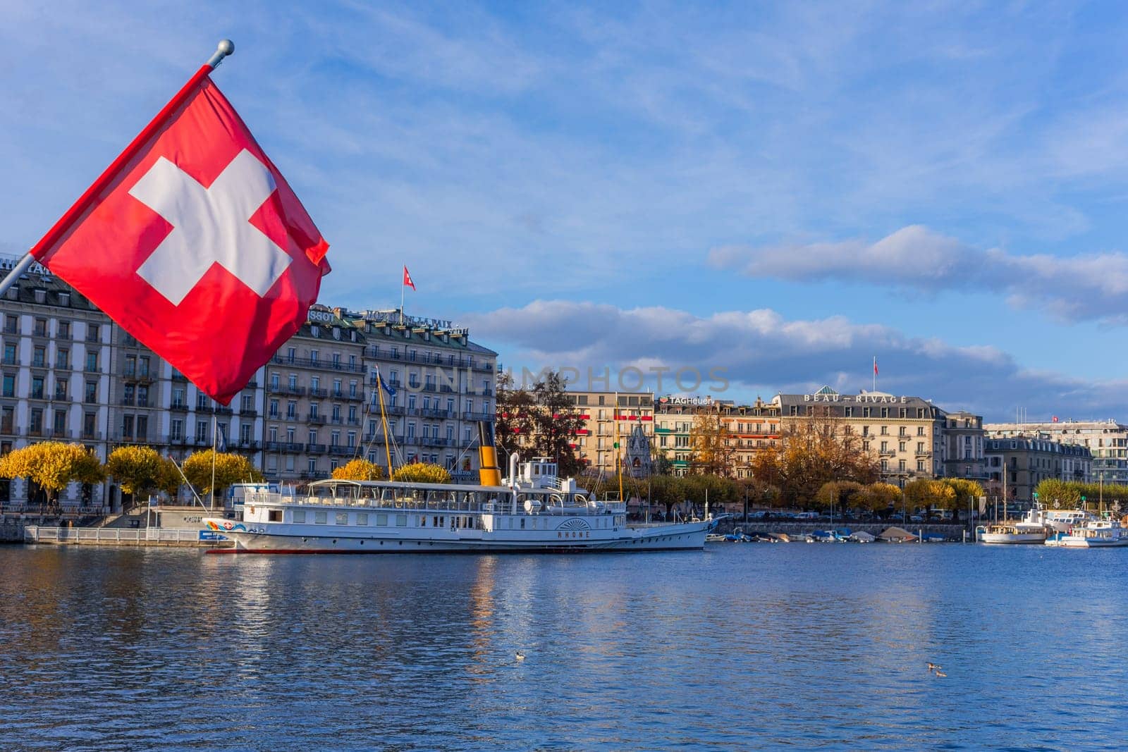Geneva, Switzerland - November 15, 2023: Swiss flag at the Pont du Mont Blanc bridge in Geneva city in Switzerland