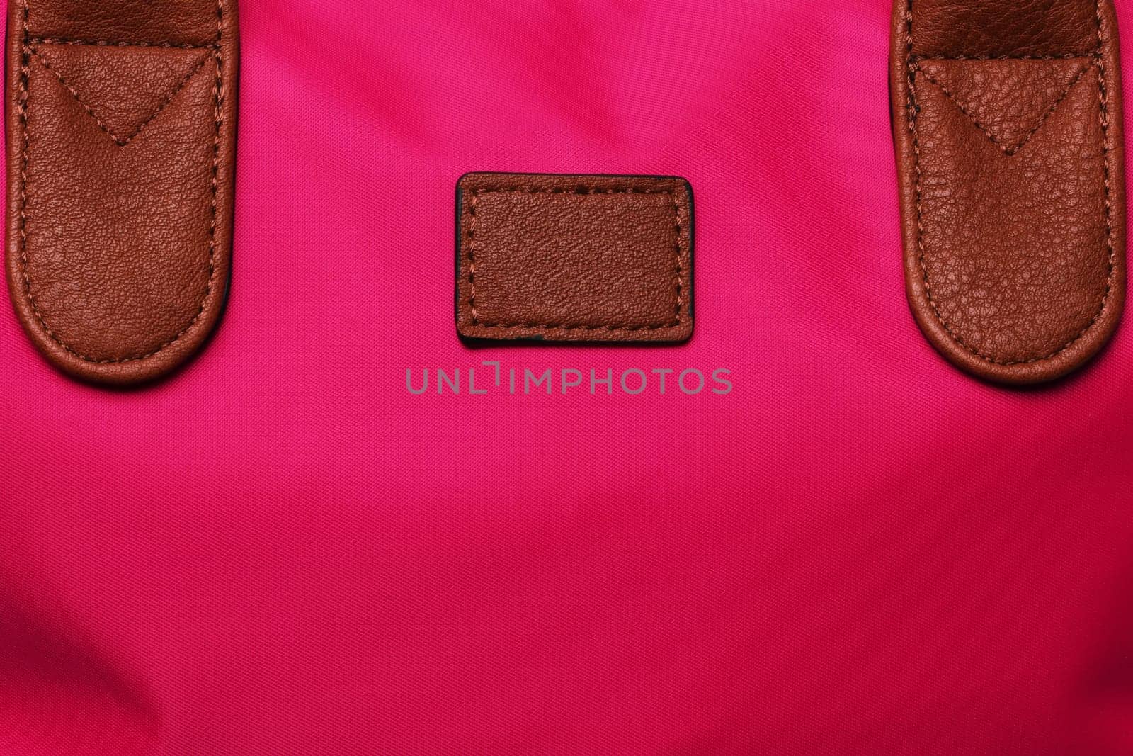 Part of a red female handbag with brown leather handles as background texture. Copy space.