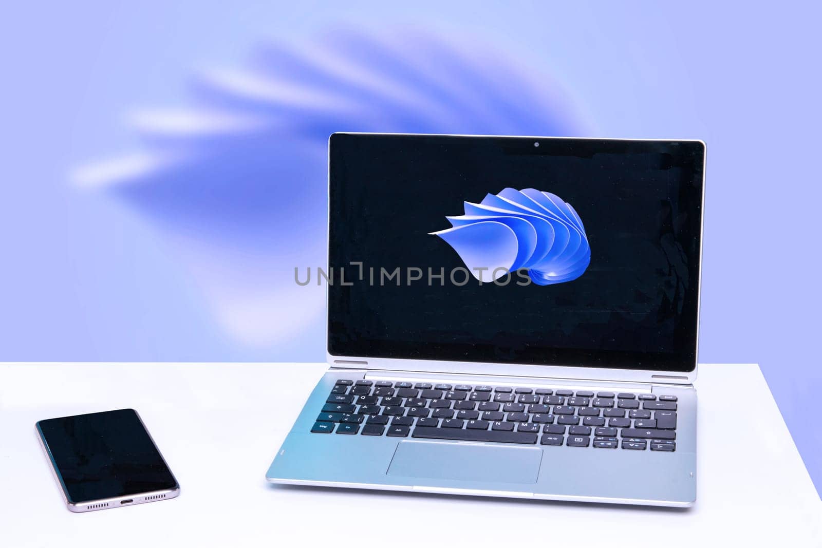 Modern white office work table or desk with portable laptop computer with abstract background and smartphone with blank screen over abstract technology background.