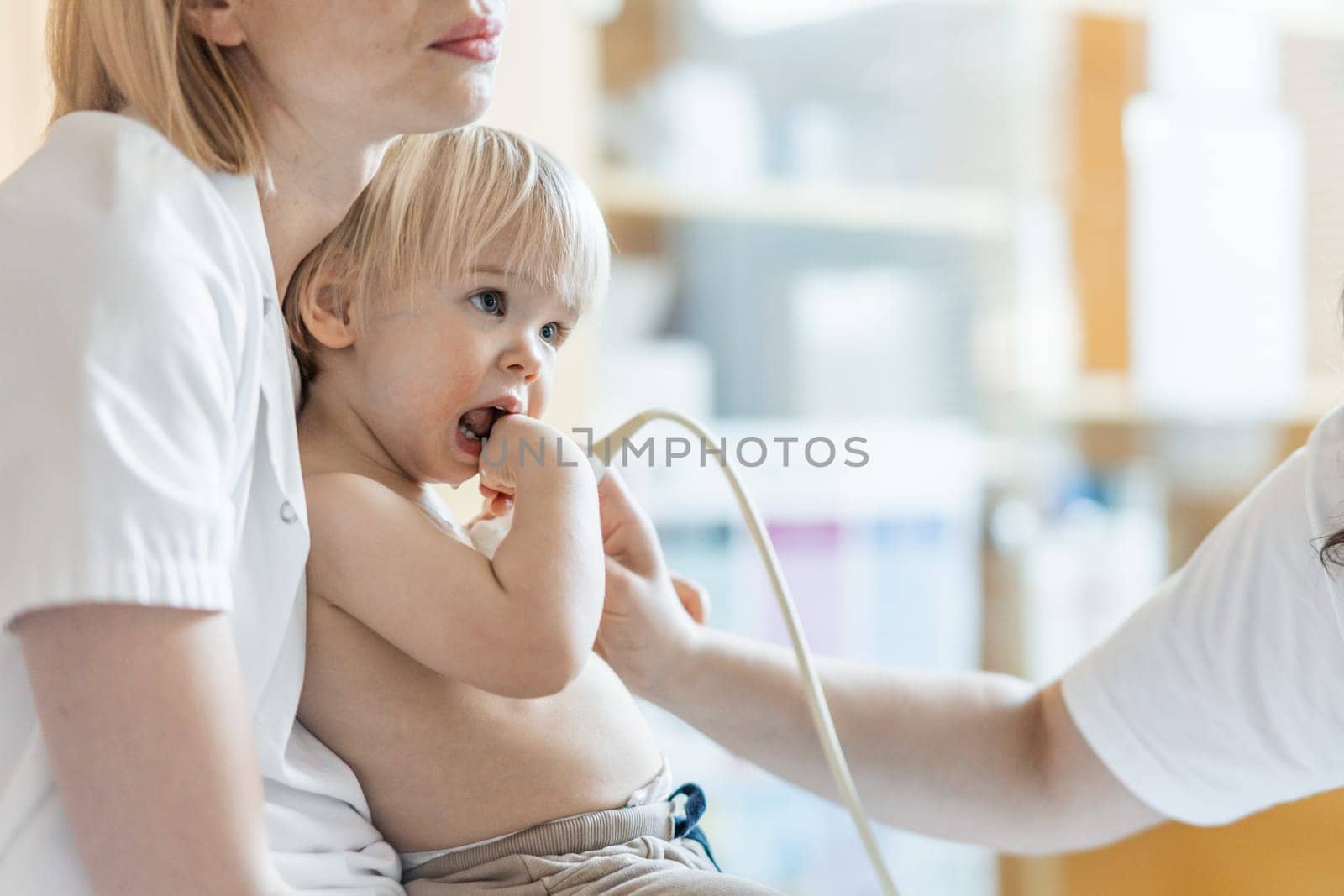 Small child being checked for heart murmur by heart ultrasound exam by cardiologist as part of regular medical checkout at pediatrician