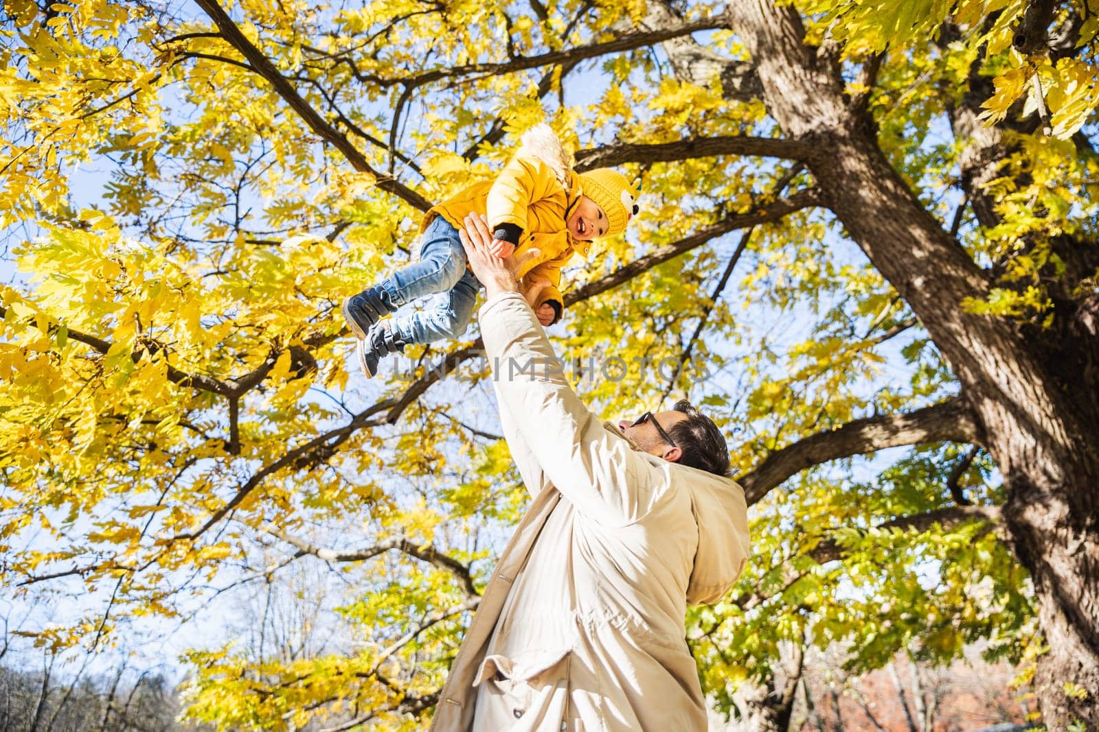 More, more,... dad, that's fun. Happy young father throws his cute little happy baby boy up in the air. Father's Day, Father and his son baby boy playing and hugging outdoors in nature in fall