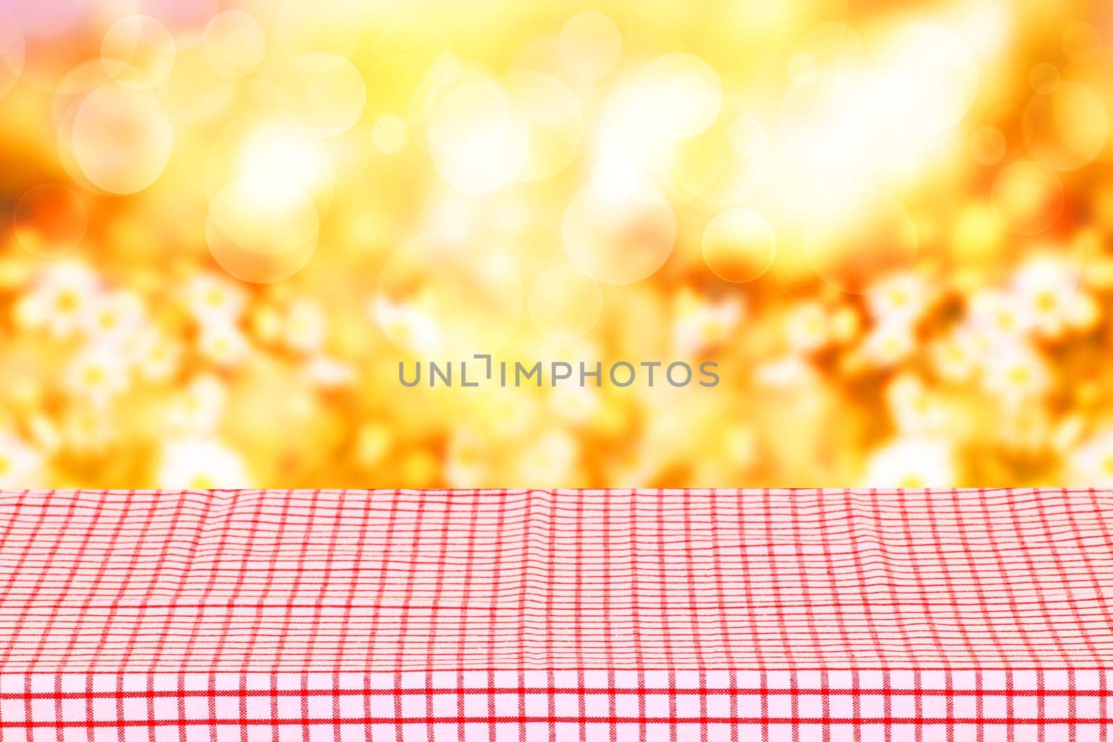 Empty table product. Empty colorful checkered tablecloth over abstract blurred natural spring background texture with space for your food and product display montage.