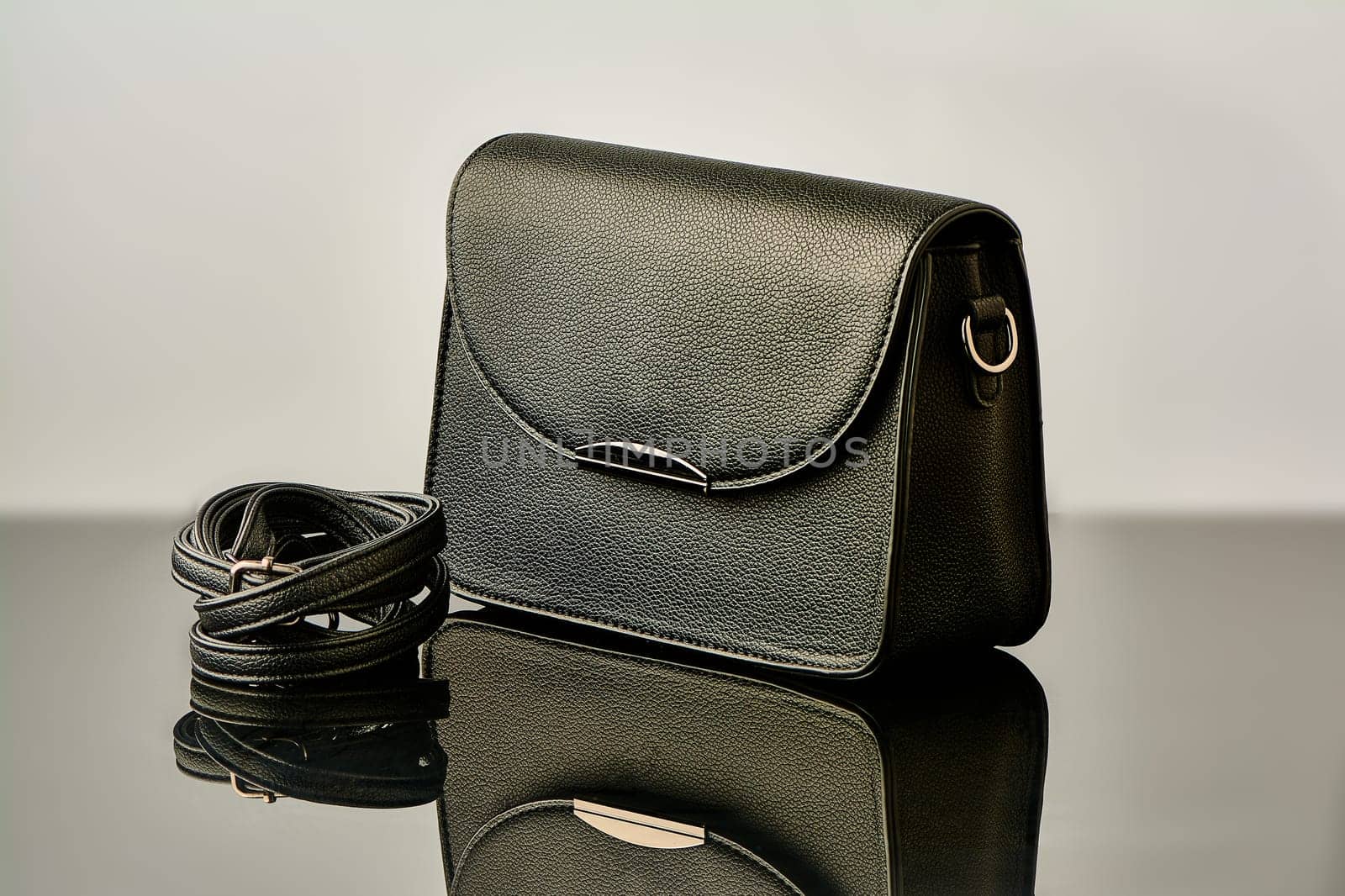 A black handbag stands on black glass. High quality photo