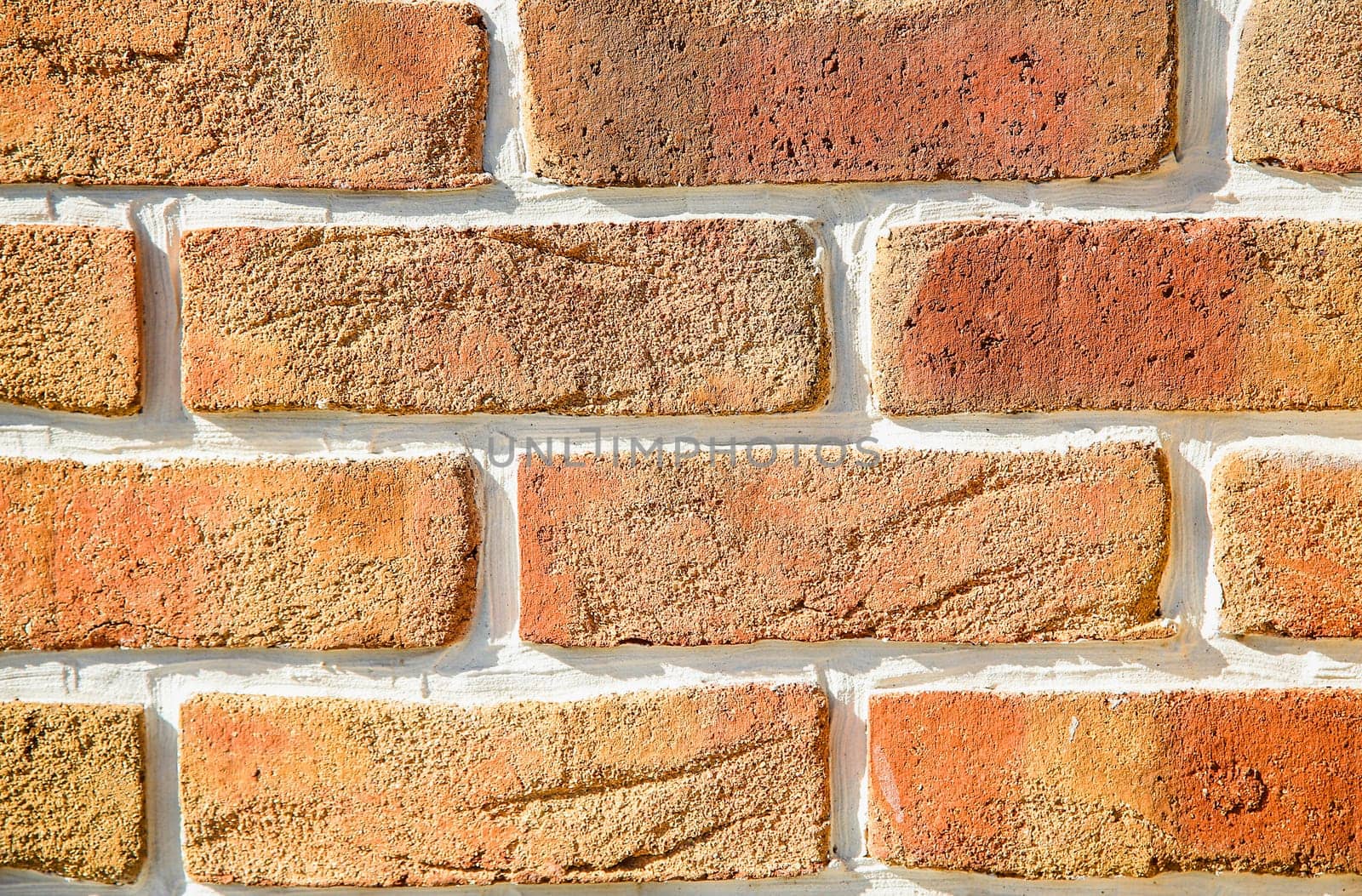 A brick wall made of cracked decorative orange bricks in close-up. Texture or background