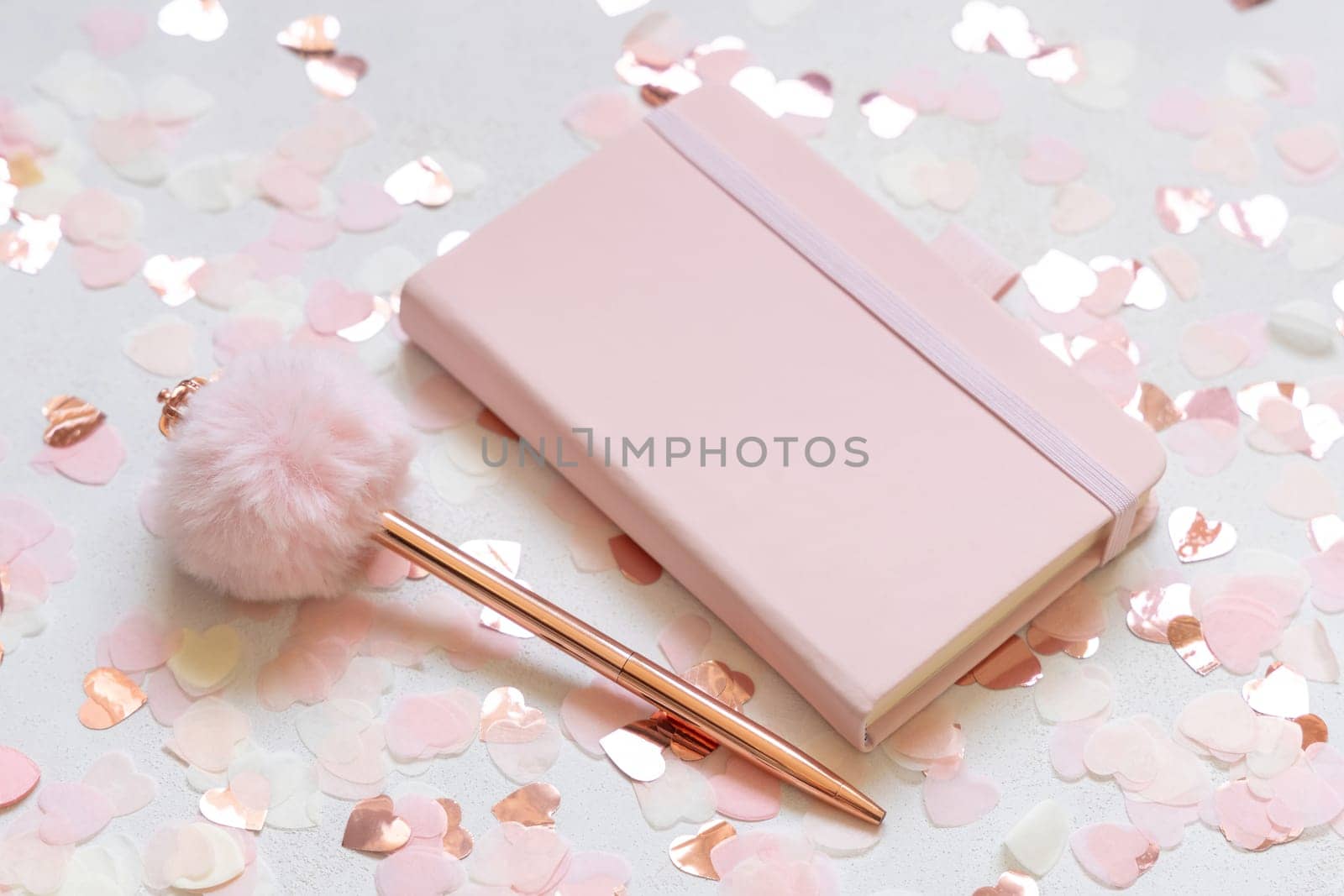 Pink hardcover notebook near hearts and fur pen on white table close up. Romantic girly mockup, Wedding, Valentines, Spring or Mothers day stationery