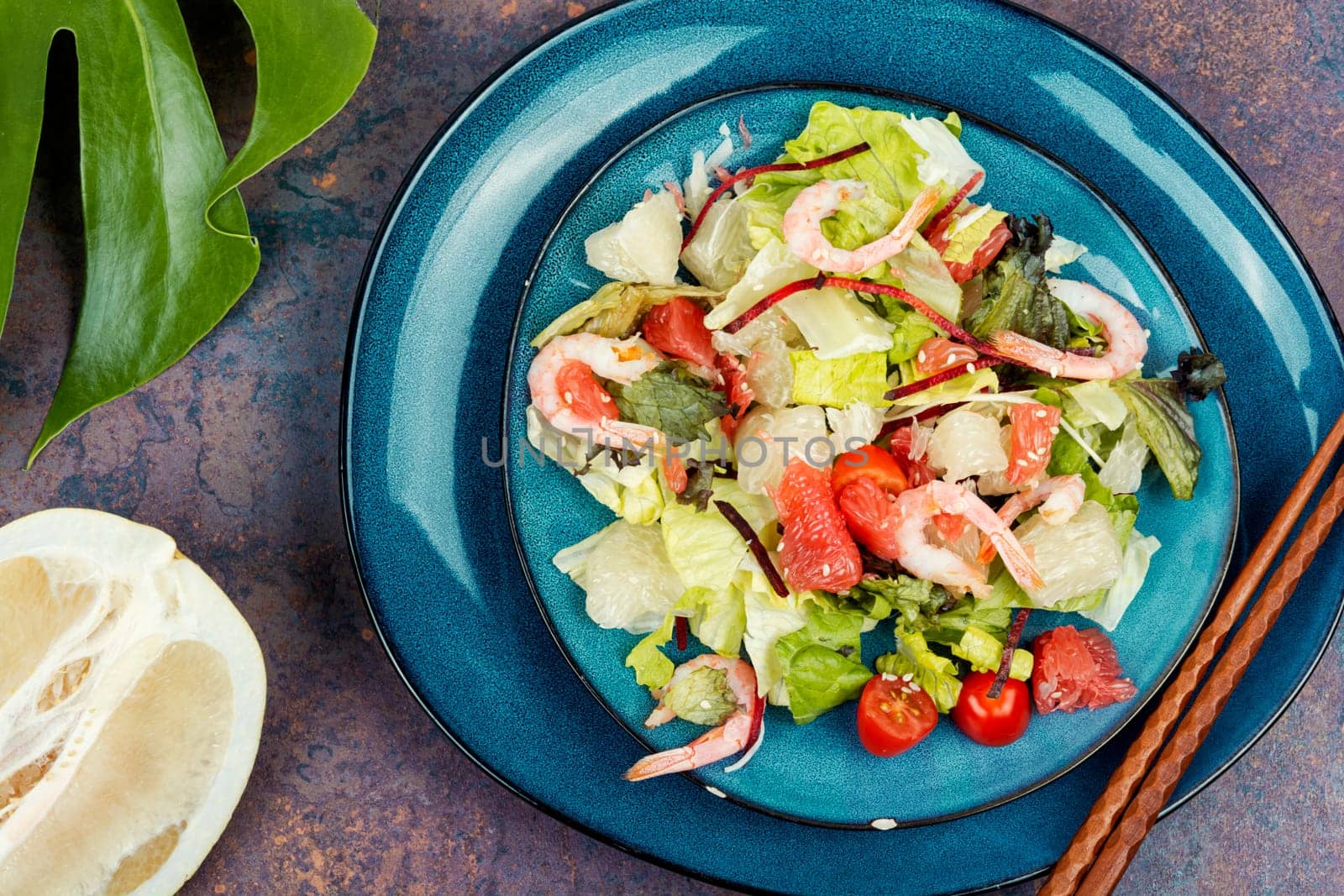 Pomelo salad with shrimp, tomatoes and lettuce on a plate.