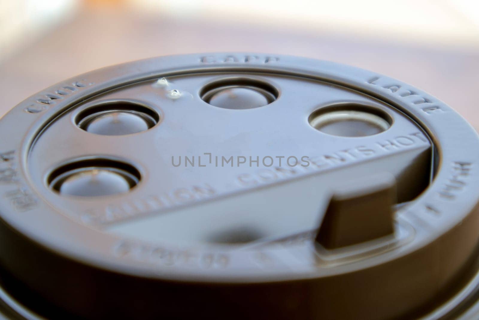 Brown plastic lid on a paper coffee cup close-up. Takeaway cup for drinks. Breakfast, coffee time. Drinks and cafe concept