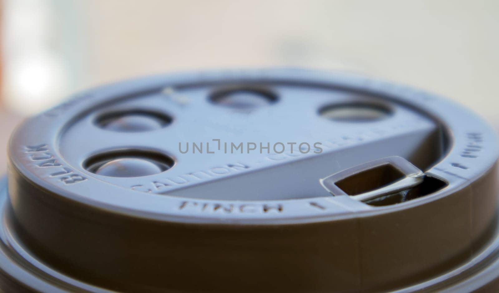 Brown plastic lid on a paper coffee cup close-up. Takeaway cup for drinks. Breakfast, coffee time. Drinks and cafe concept