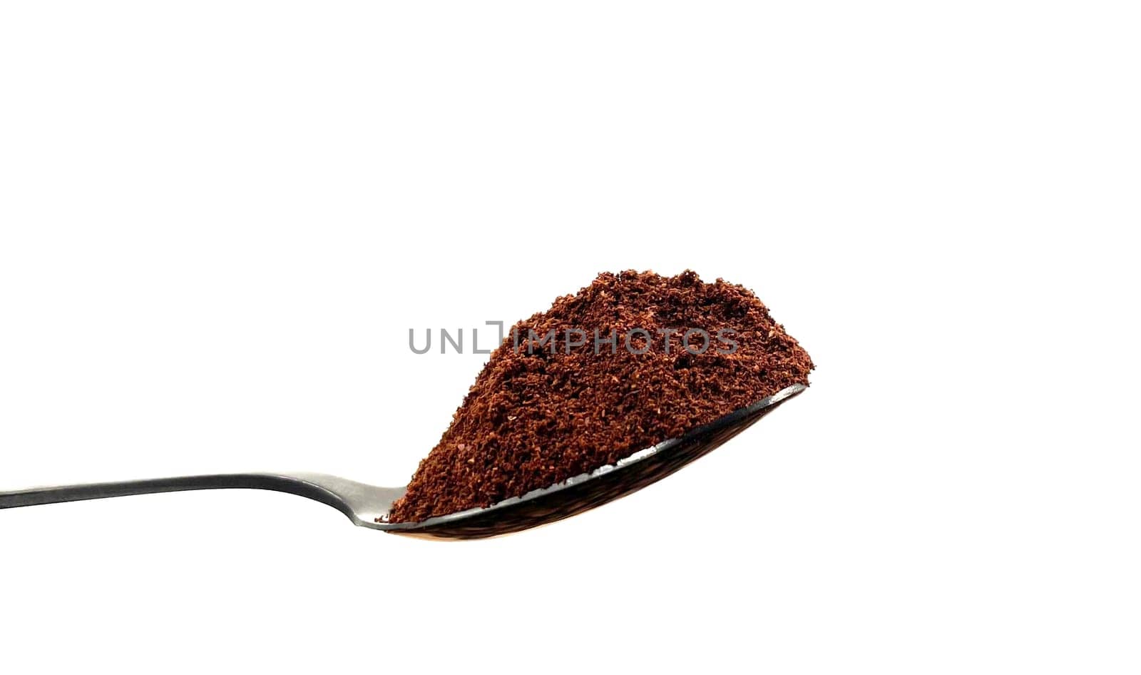 Ground coffee powder in a stainless steel teaspoon isolated on a white background