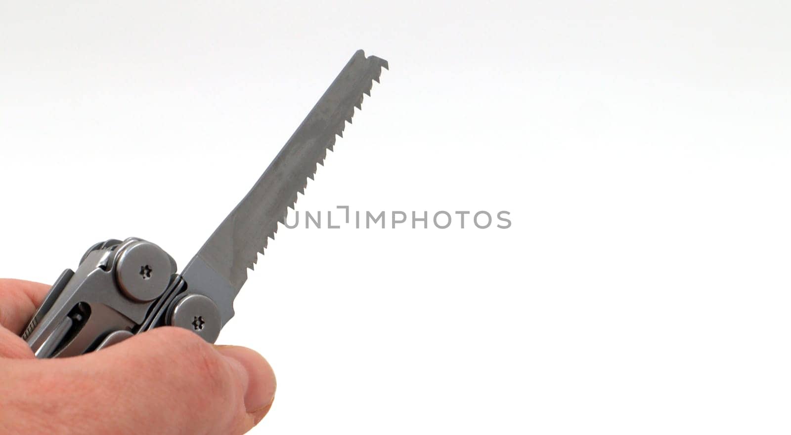 On a white background, a man's hand holds a steel multi-tool or pocket knife with an open saw. Compact and portable multi-tasking multitool with many tools. EDC concept. A tool for daily practice