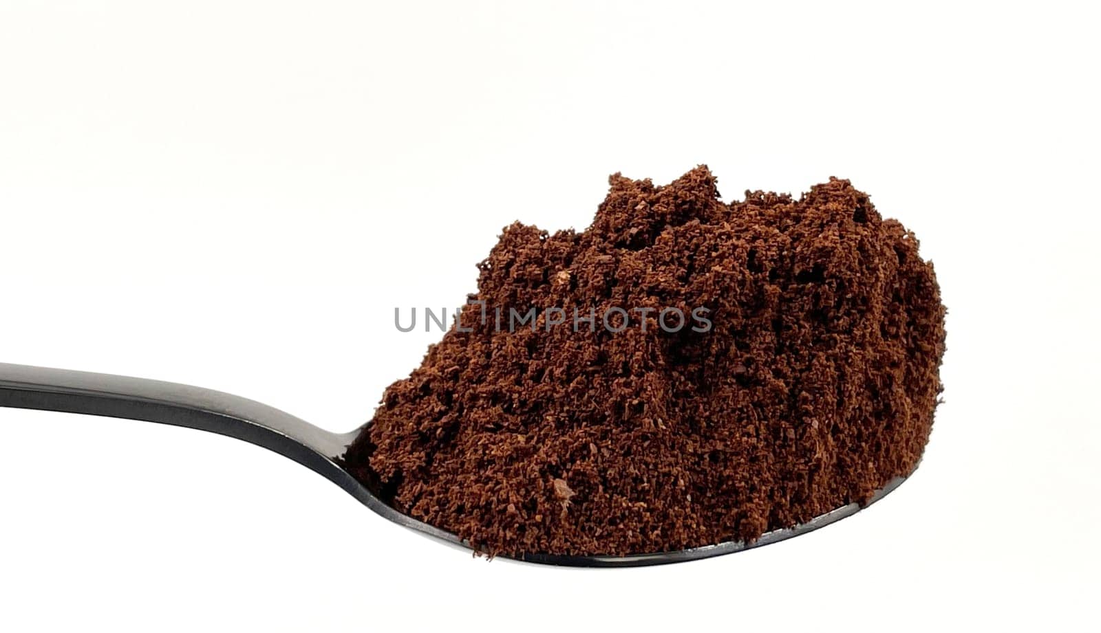 Ground coffee powder in a stainless steel teaspoon isolated on a white background