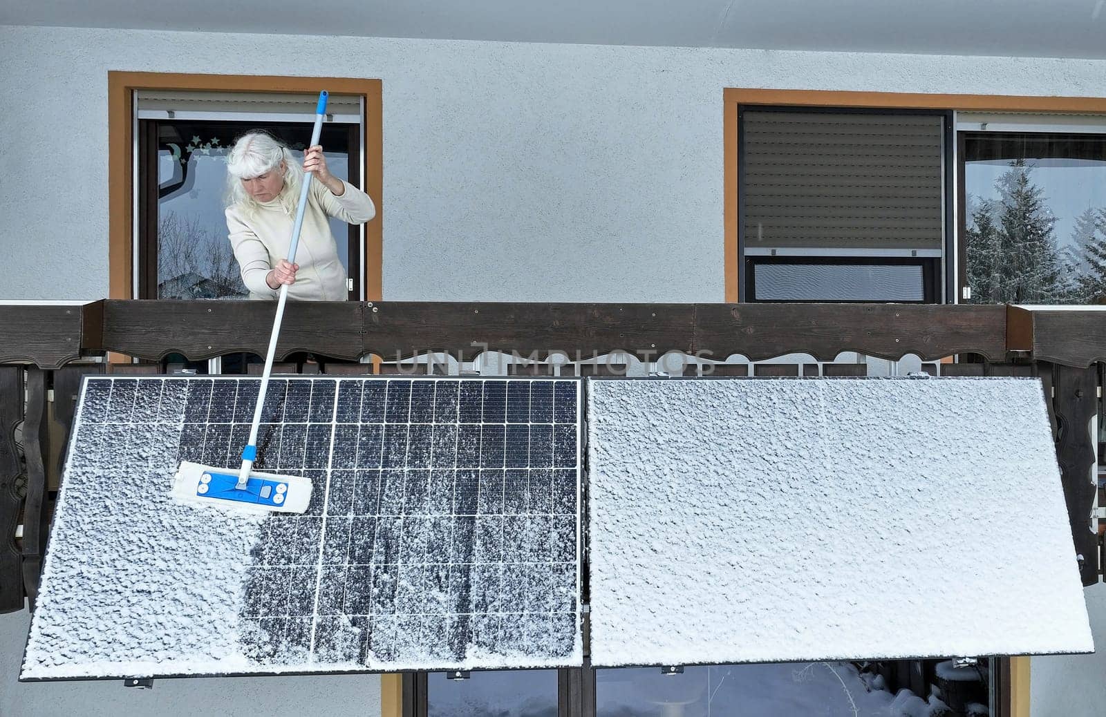 A woman removes snow from a balcony power station in winter