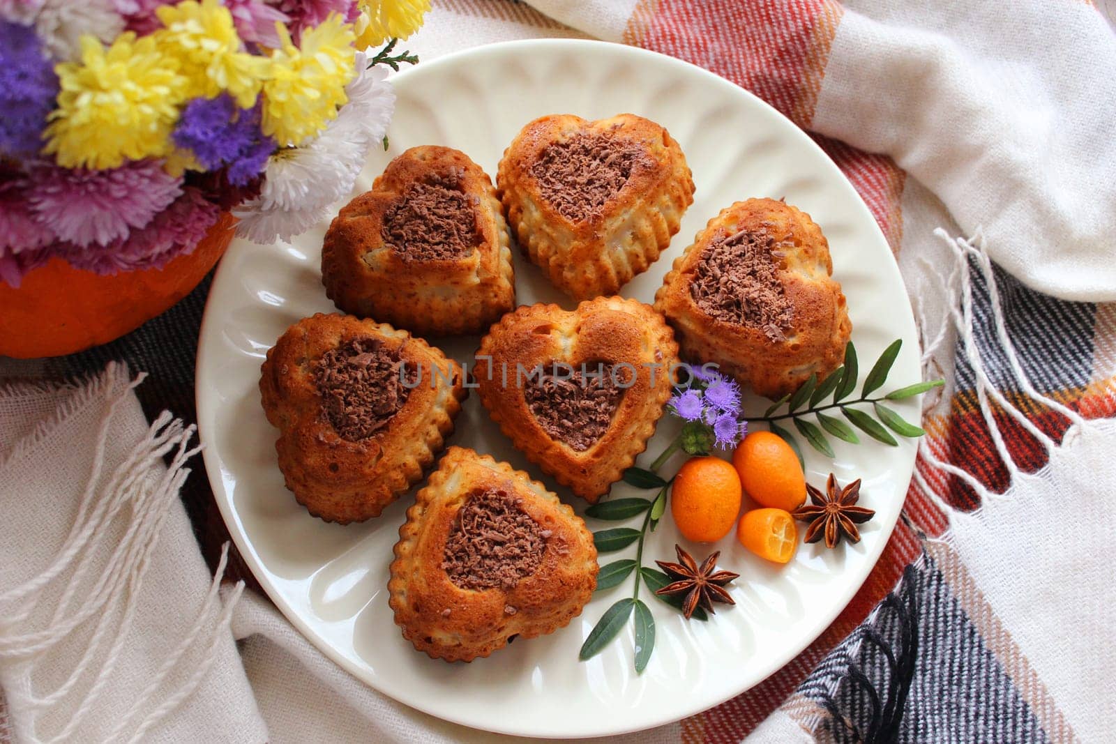 Six cupcakes in the shape of hearts decorated with grated chocolate and small kumquats