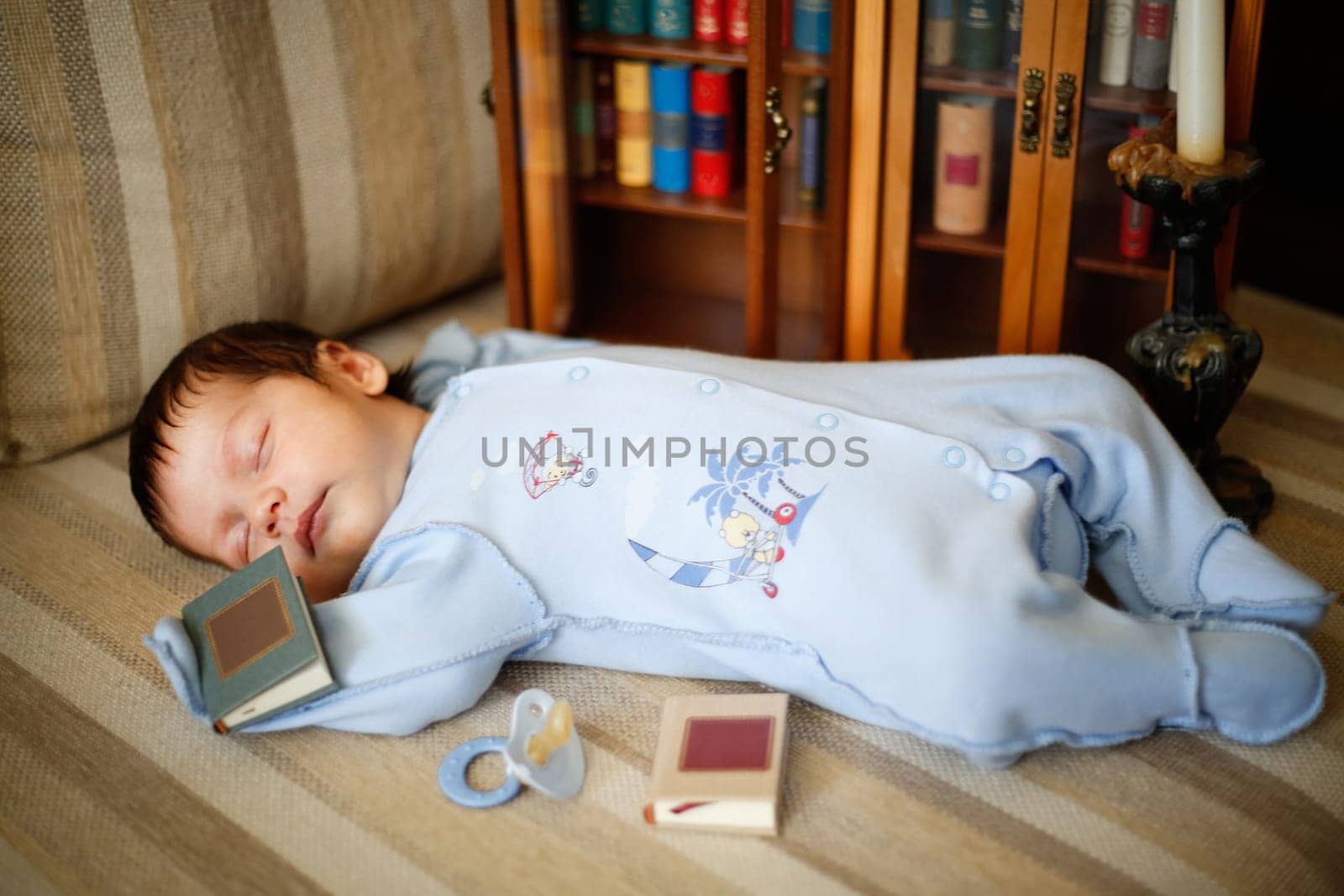 A little kid fell asleep on the couch next to books and a pacifier close-up view from an angle