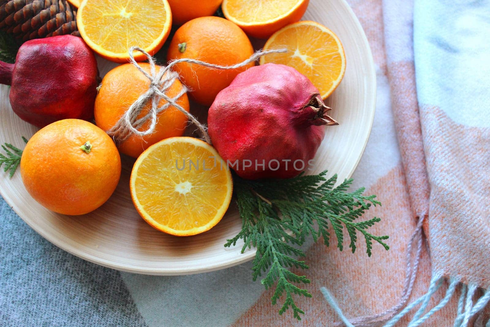 A fruit platter of orange and pomegranate fruits in close-up on top of a white plate
