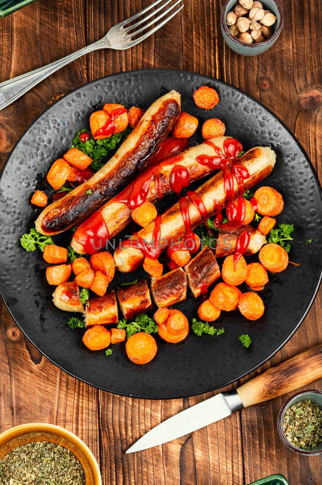 Grilled turkey sausages with roasted carrots on the plate. Copy space.