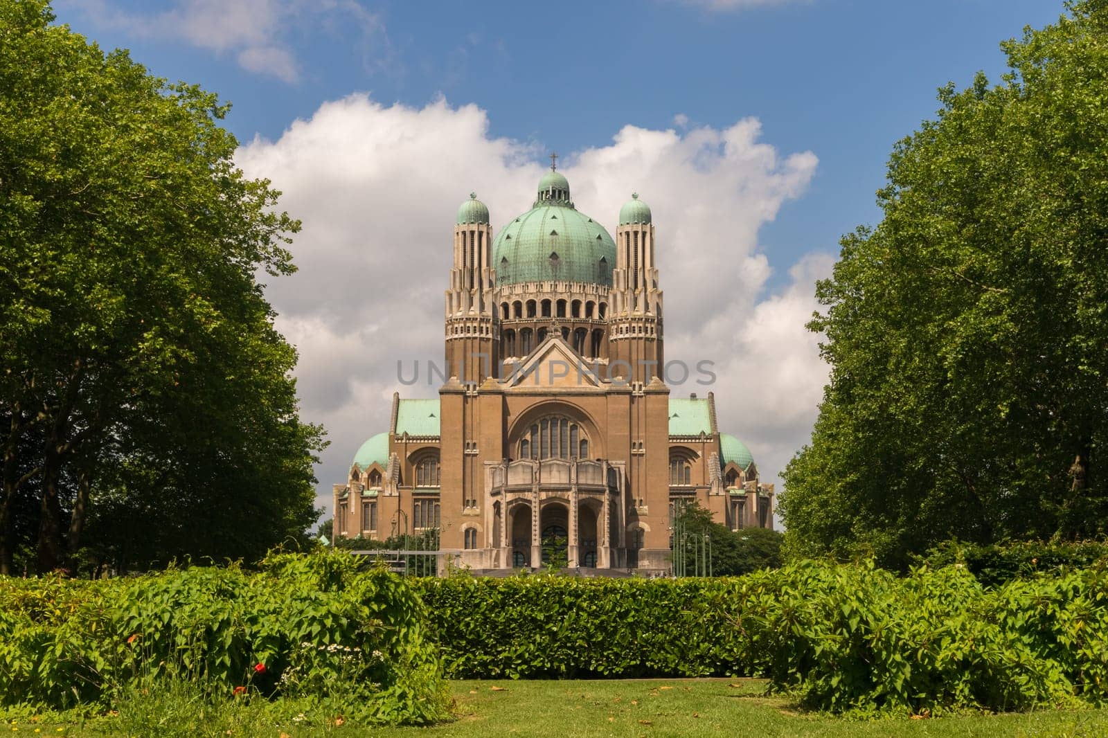 The National Basilica of the Sacred Heart in Brussels ranks fifth among the largest churches in the world. The large Art Deco building is catched in moderate sunlight against a light-blue sky with few clouds.