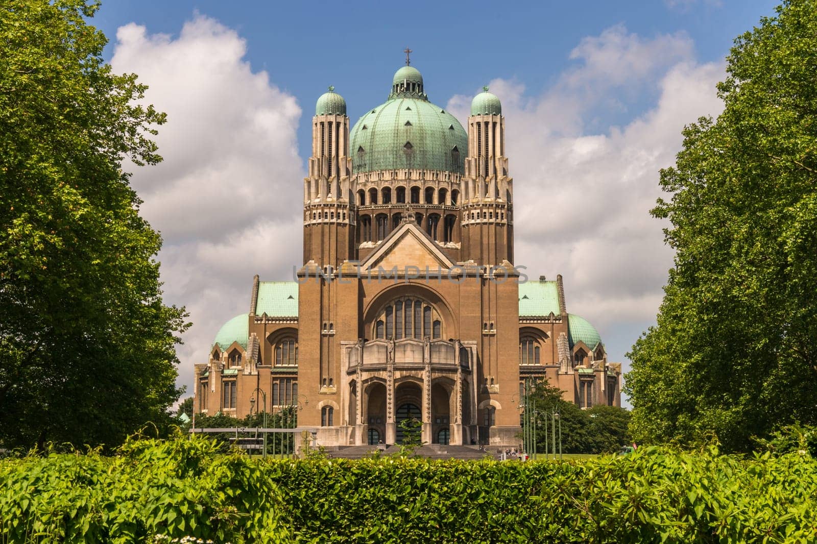 The National Basilica of the Sacred Heart in Brussels ranks fifth among the largest churches in the world. The large Art Deco building is catched in moderate sunlight against a light-blue sky with few clouds.