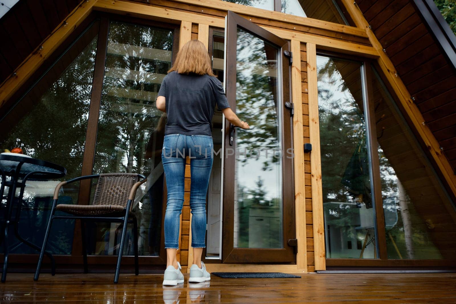 Back view of a woman opening the door of a country house and enters inside