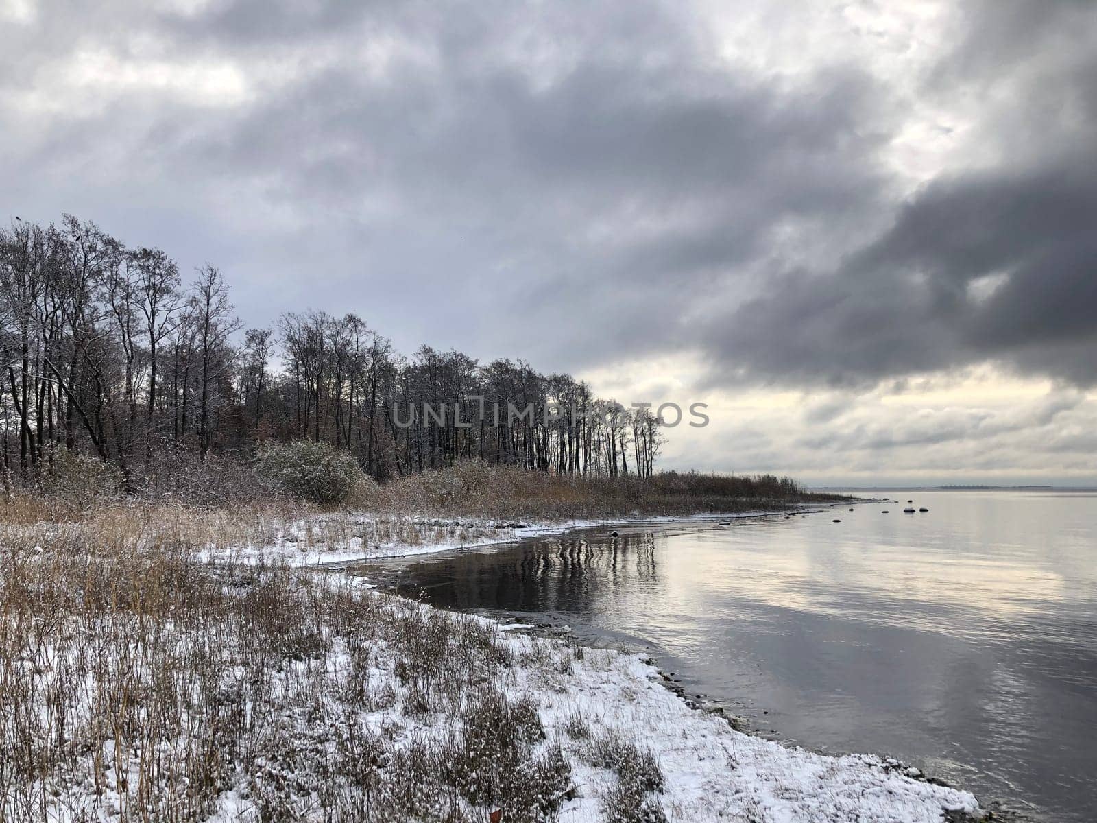 Winter landscape of the shore of the Gulf of Finland, dramatic clouds reflected in the sea