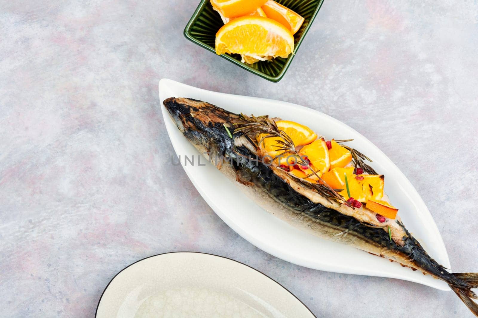 Mackerel fish baked with oranges and rosemary on a vintage wooden background.