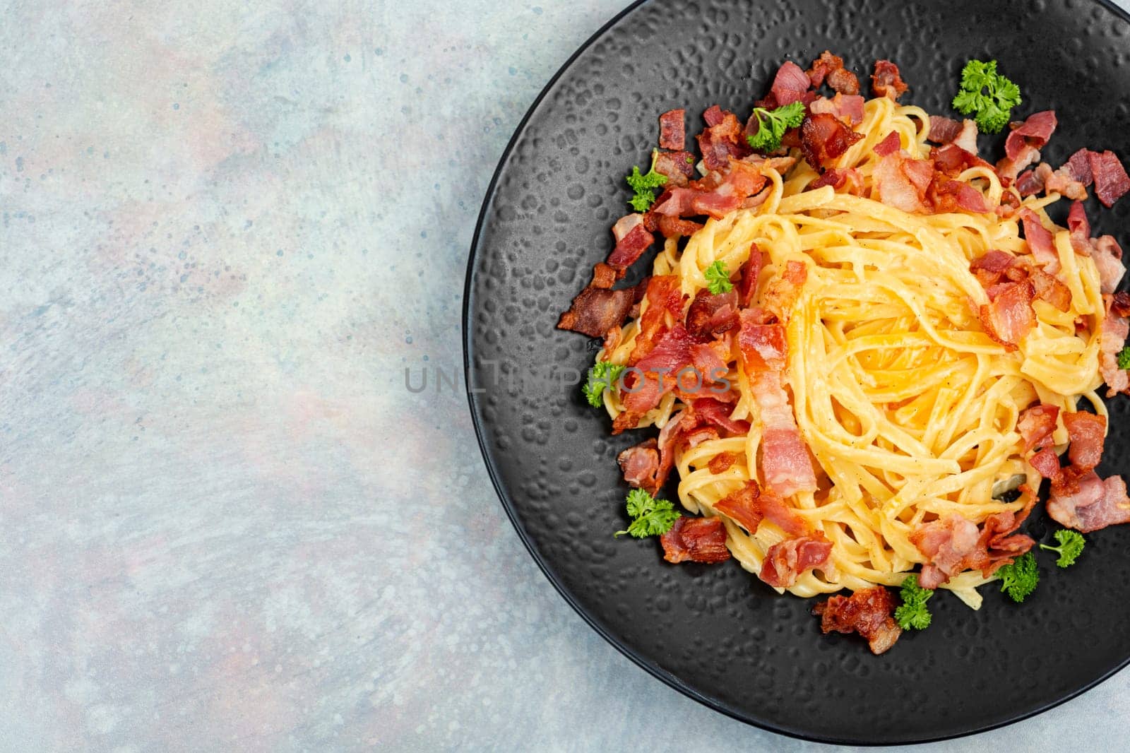 Homemade pasta with fried bacon on a plate, pasta carbonara. Space for text.