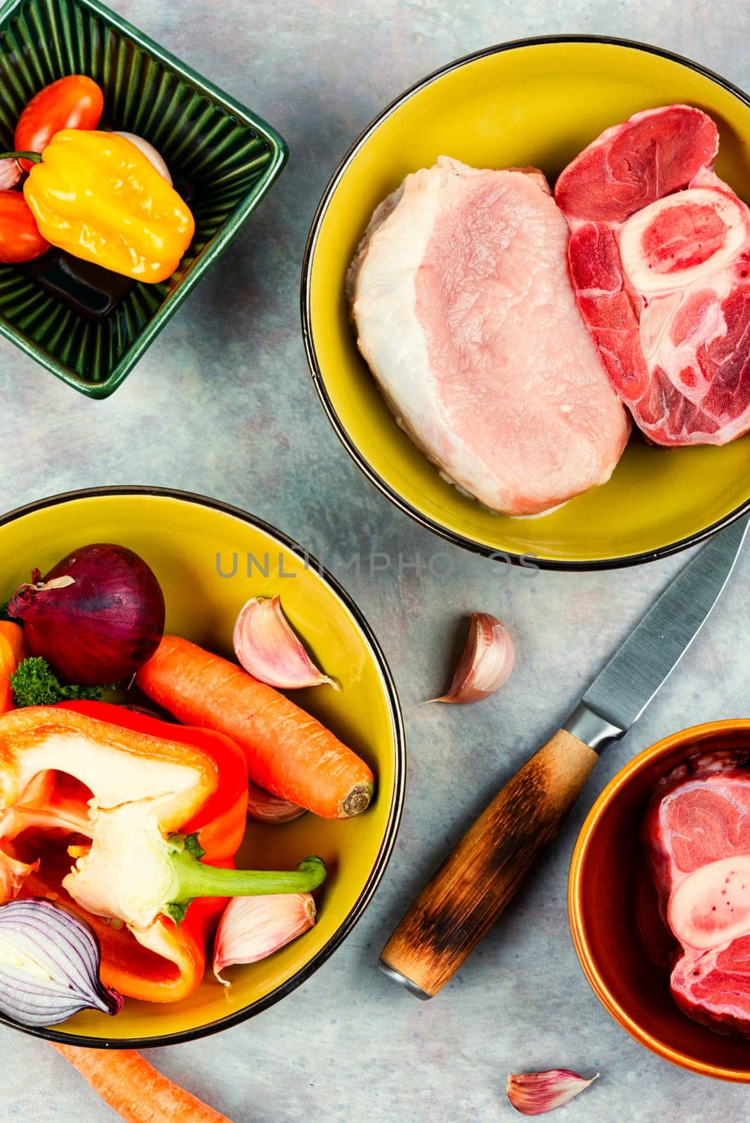 Raw piece uncooked meat and different vegetables on the kitchen table. Set of ingredients for soup. Top view, flat lay.