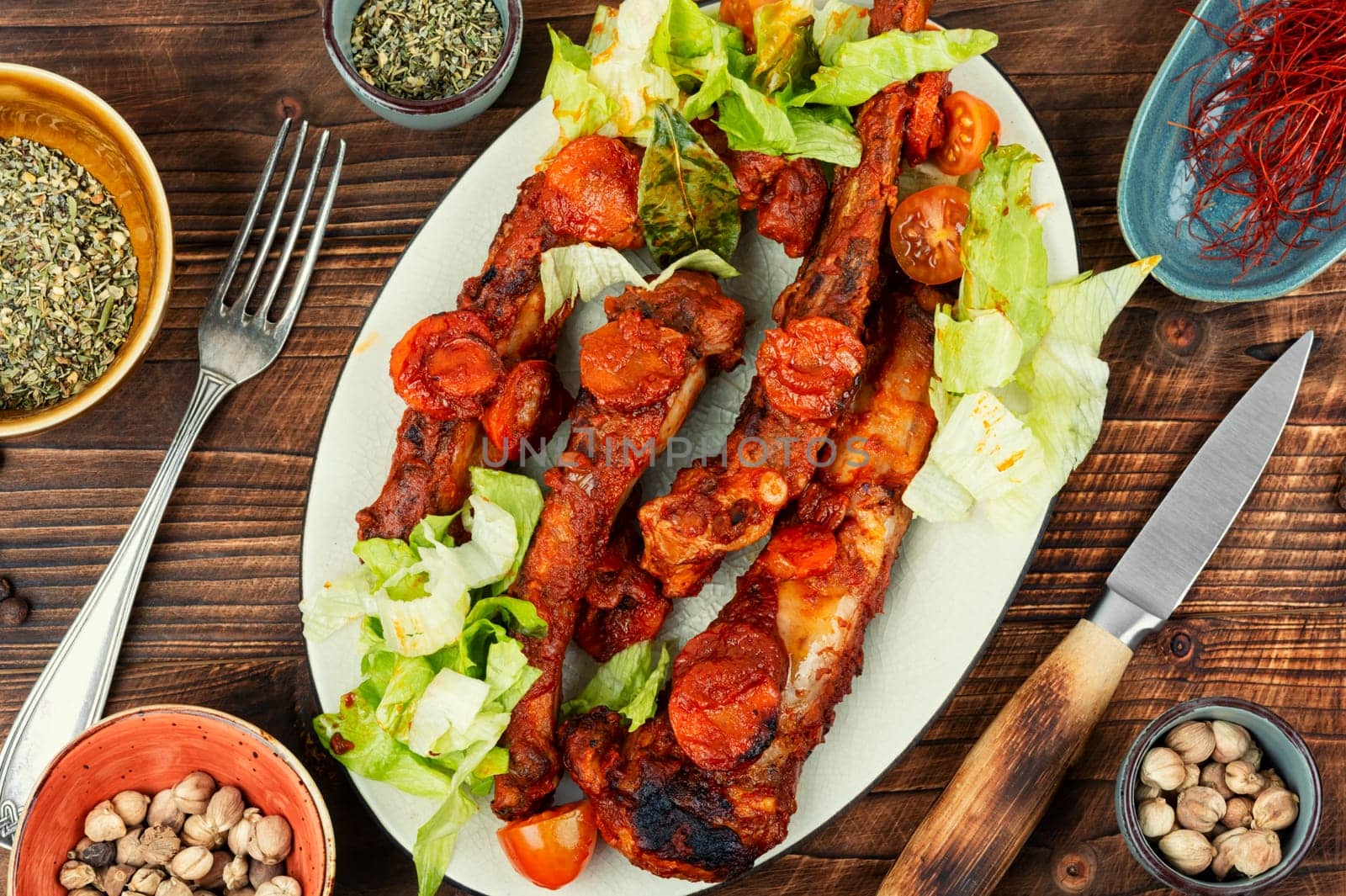 Braised pork ribs in tomato sauce served on a plate.